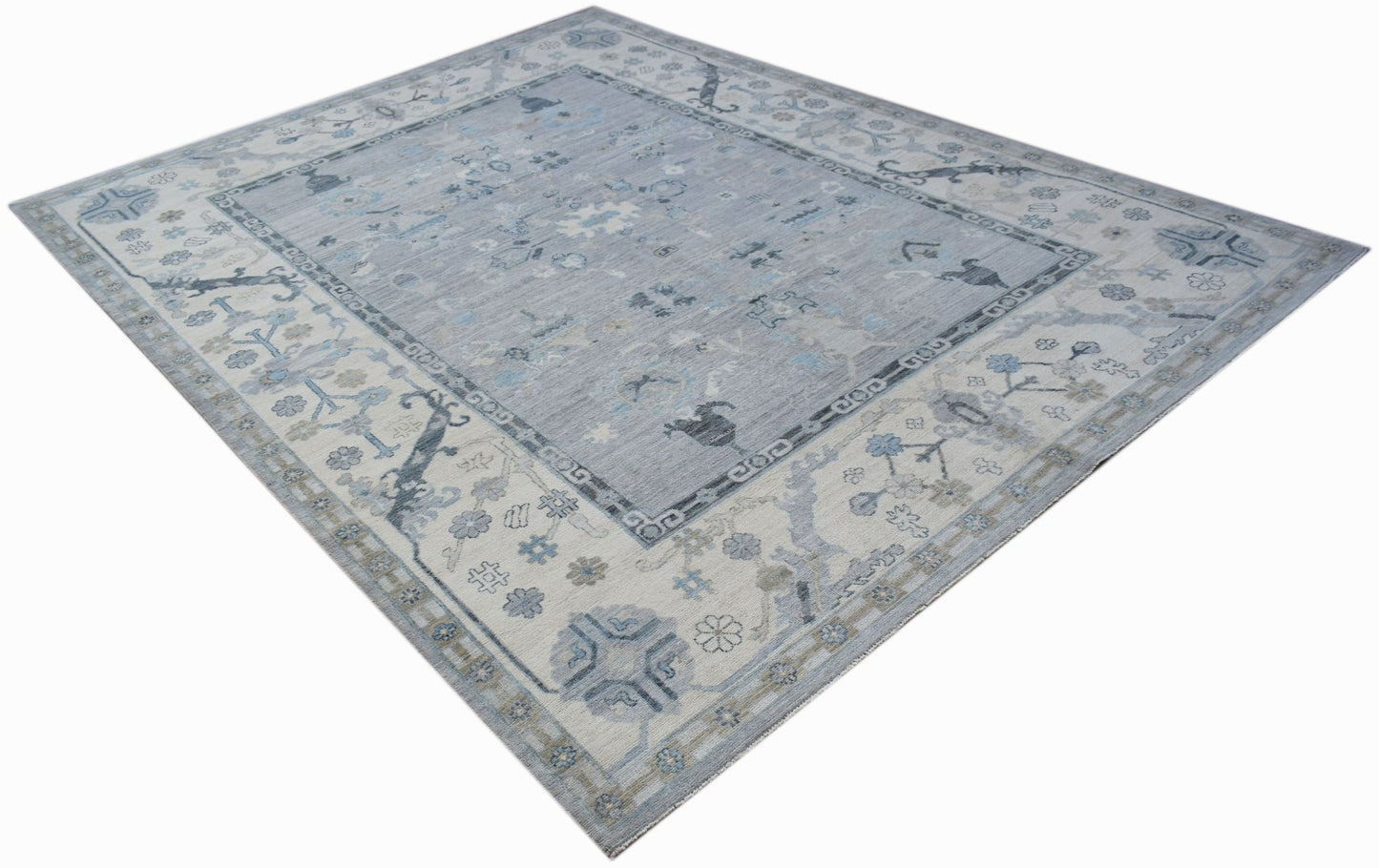 A handwoven transitional Oushak rug featuring a light blue and cream floral pattern.