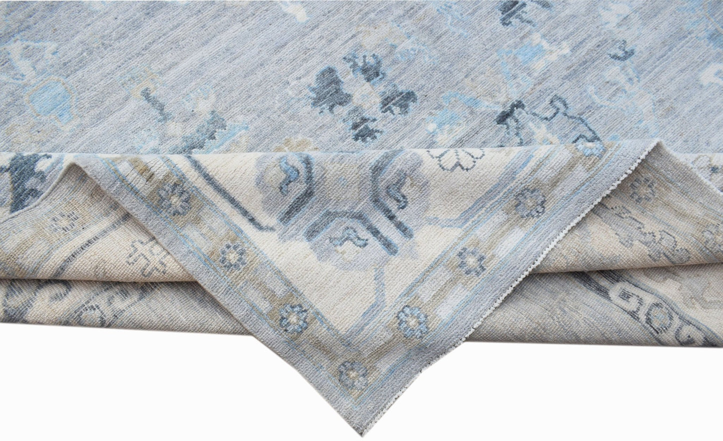 A handwoven transitional Oushak rug in shades of blue and cream with a floral pattern.