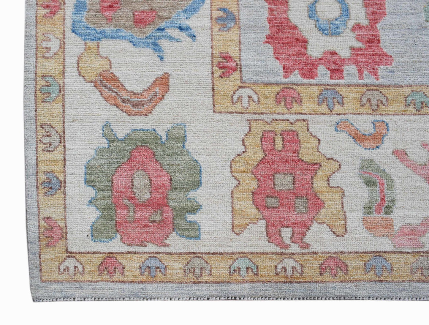 A handwoven transitional Oushak rug featuring a light background with colorful floral motifs.