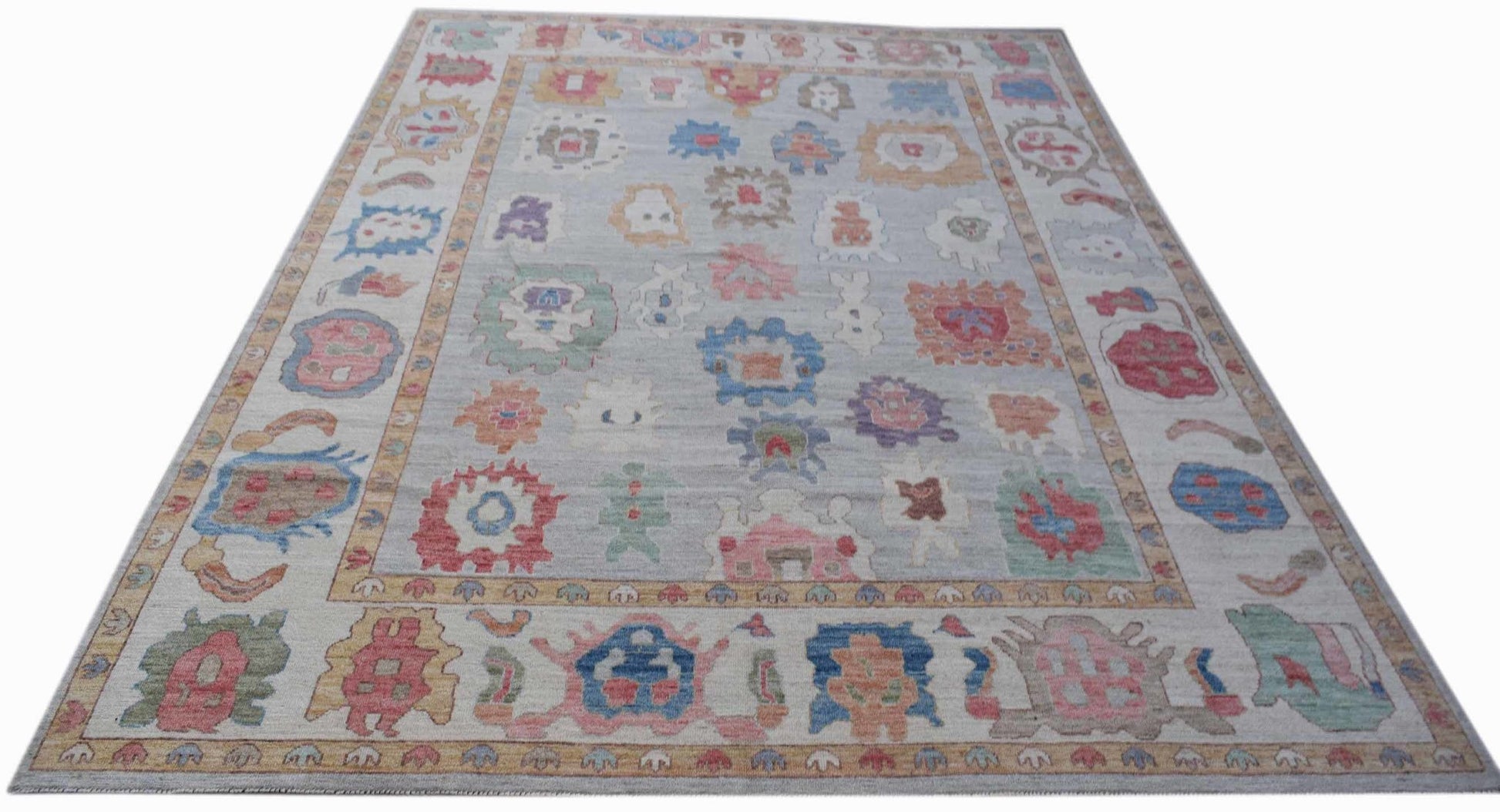 A handwoven transitional Oushak rug featuring a light grey field with colorful floral motifs.