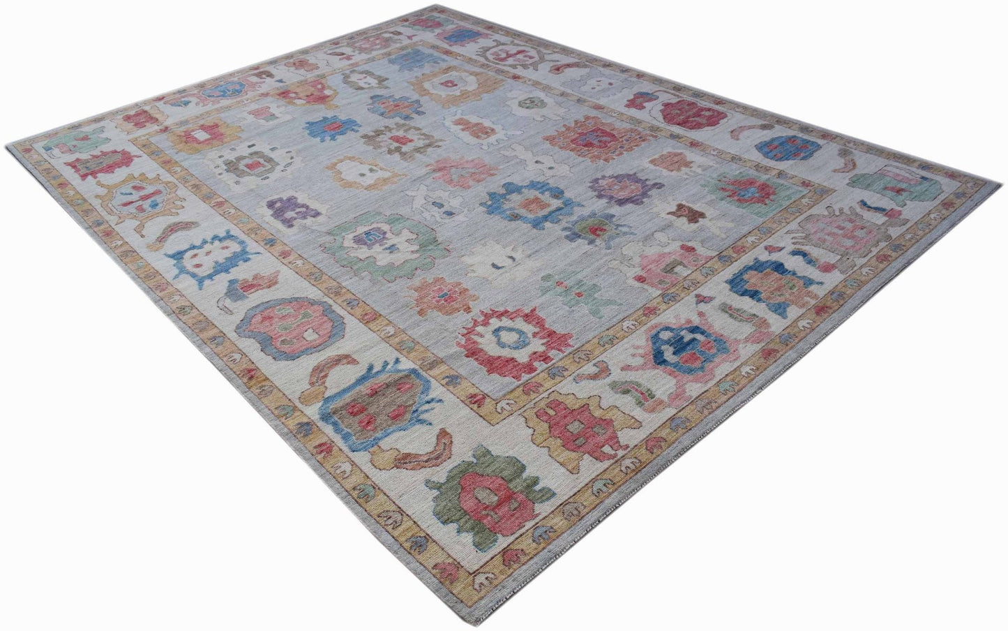 A handwoven transitional Oushak rug featuring a light grey field with colorful floral motifs.