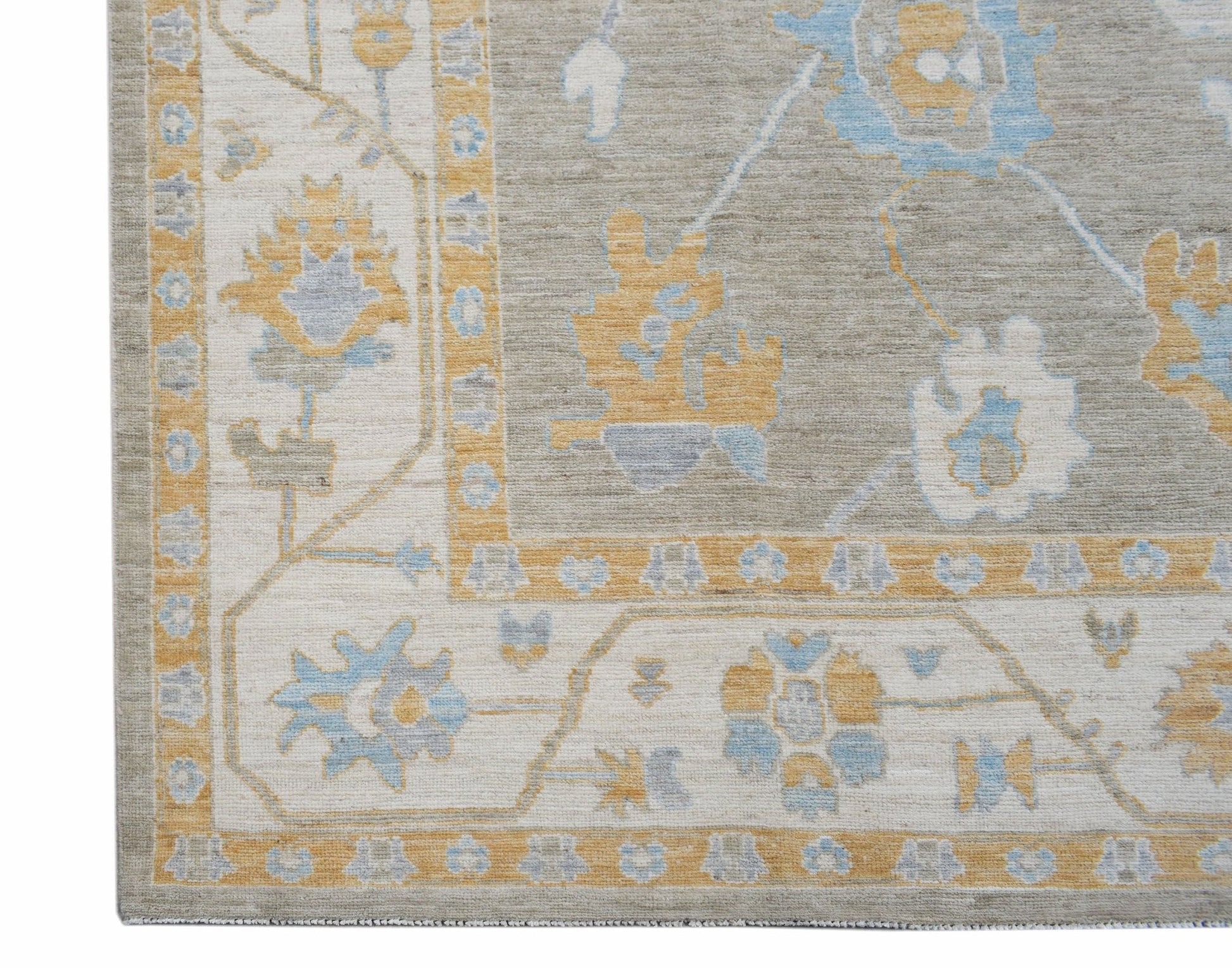A handwoven transitional Oushak rug featuring a floral pattern in soft blue, yellow, and grey.