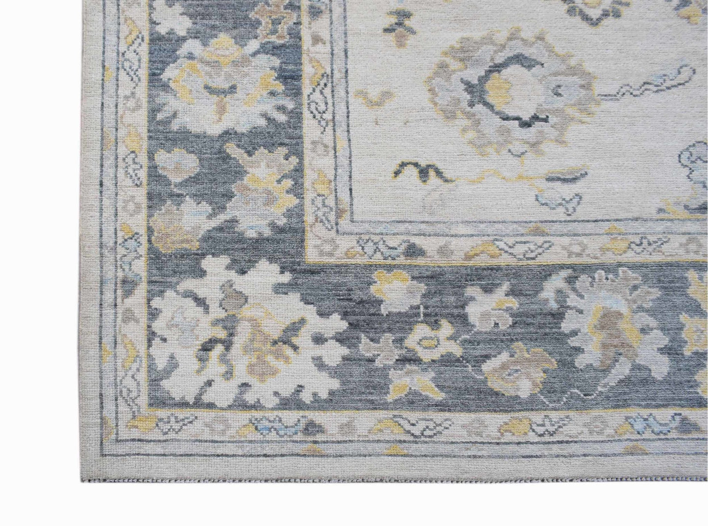 A handwoven transitional Oushak rug featuring a floral pattern in grey, cream, and yellow tones.
