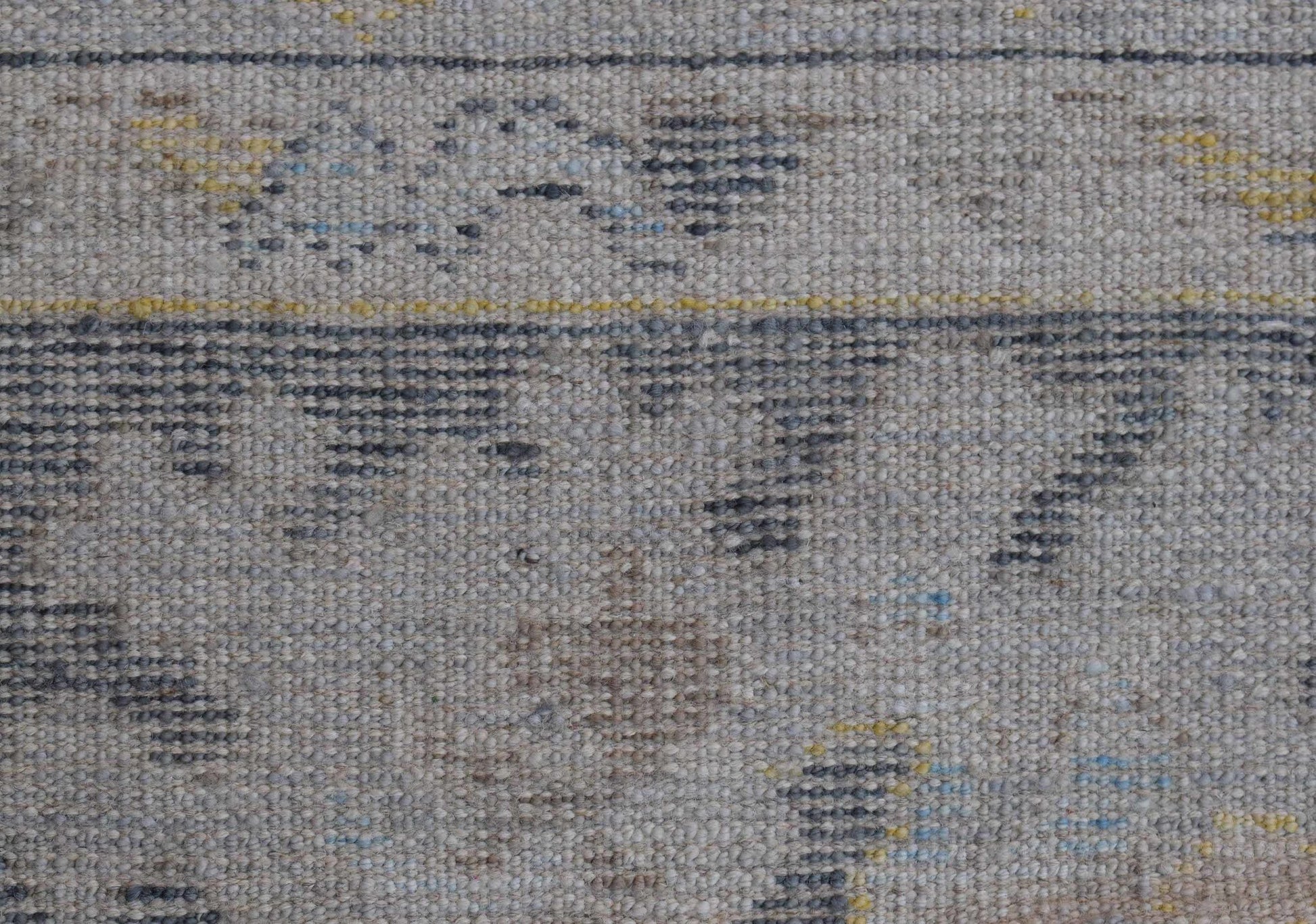 A handwoven wool Oushak rug featuring a transitional pattern in grey, blue, and yellow tones.