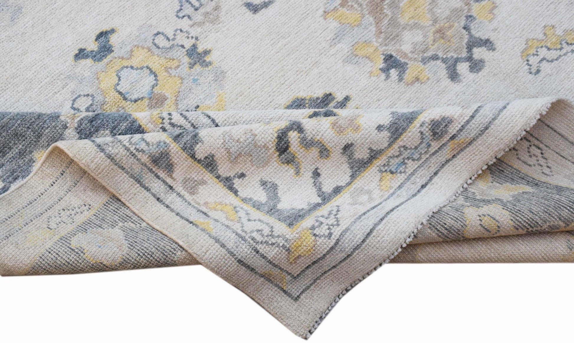 A handwoven transitional Oushak rug featuring a floral pattern in grey, yellow, and cream tones.