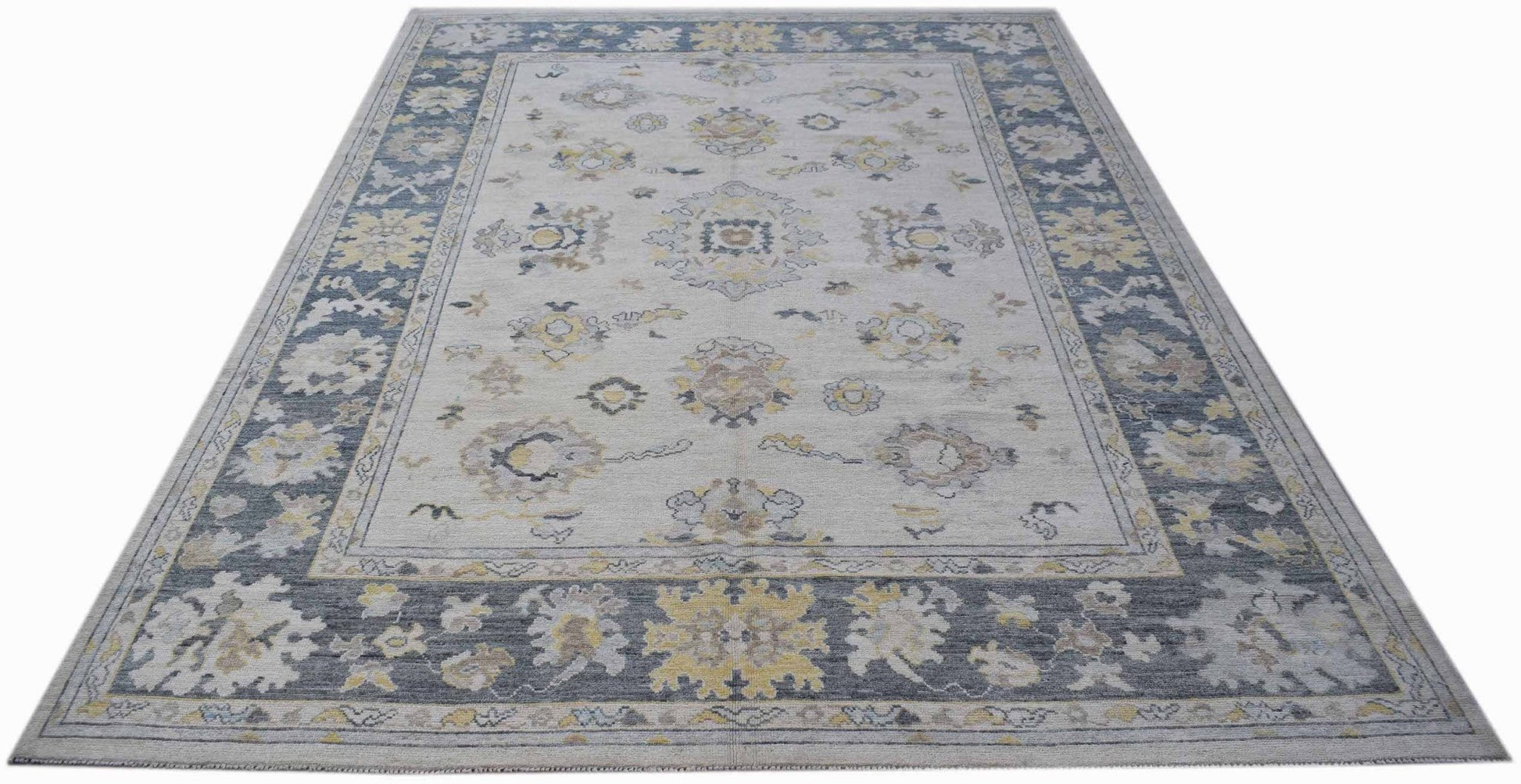 A handwoven transitional Oushak rug featuring a floral pattern in blue, grey, and yellow tones.