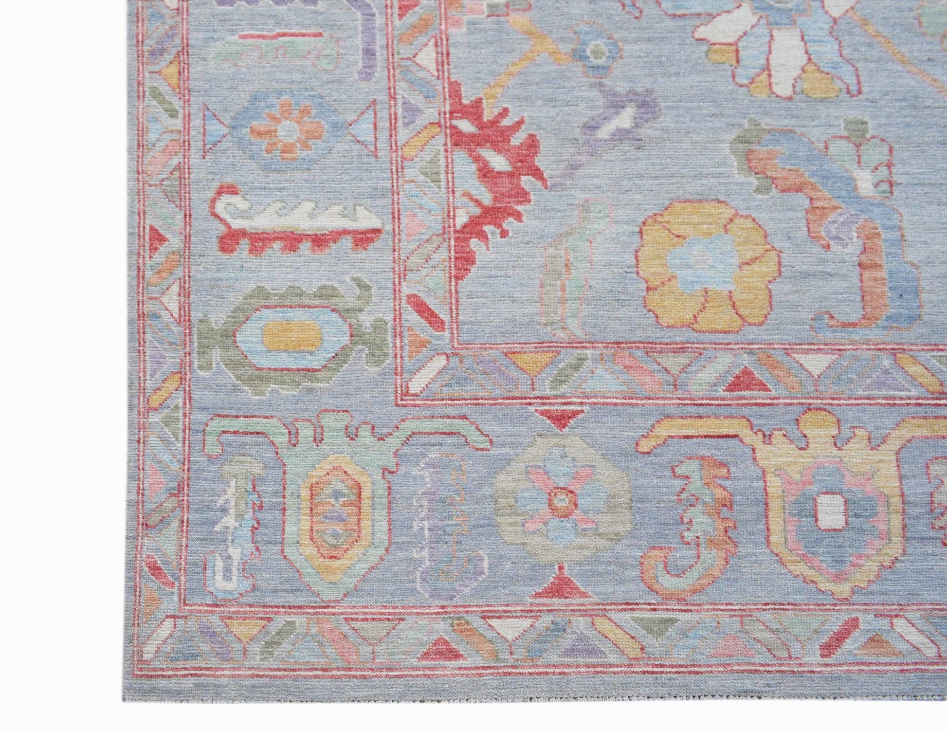 A handwoven transitional Oushak rug featuring a light blue field with colorful floral motifs.
