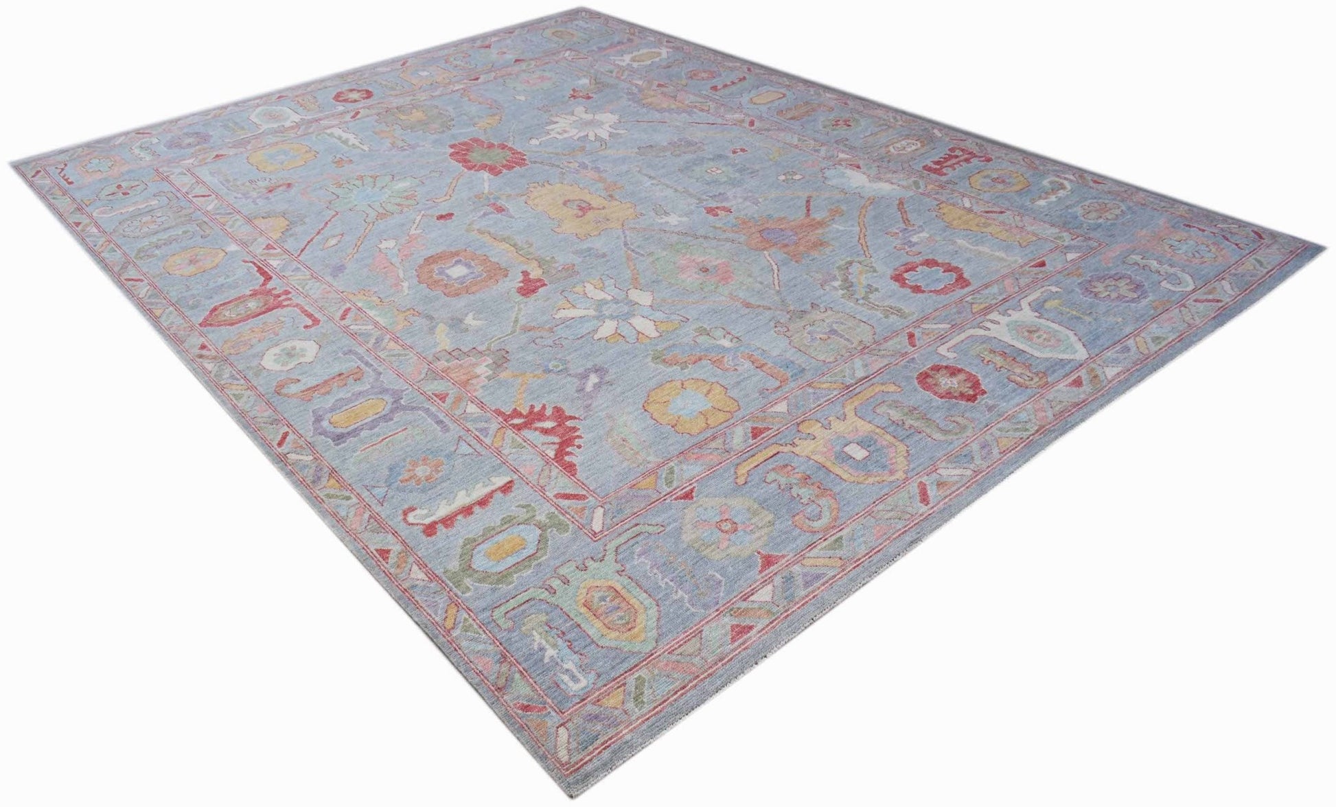 A handwoven transitional Oushak rug featuring a floral pattern in soft blue and multi-colored tones.