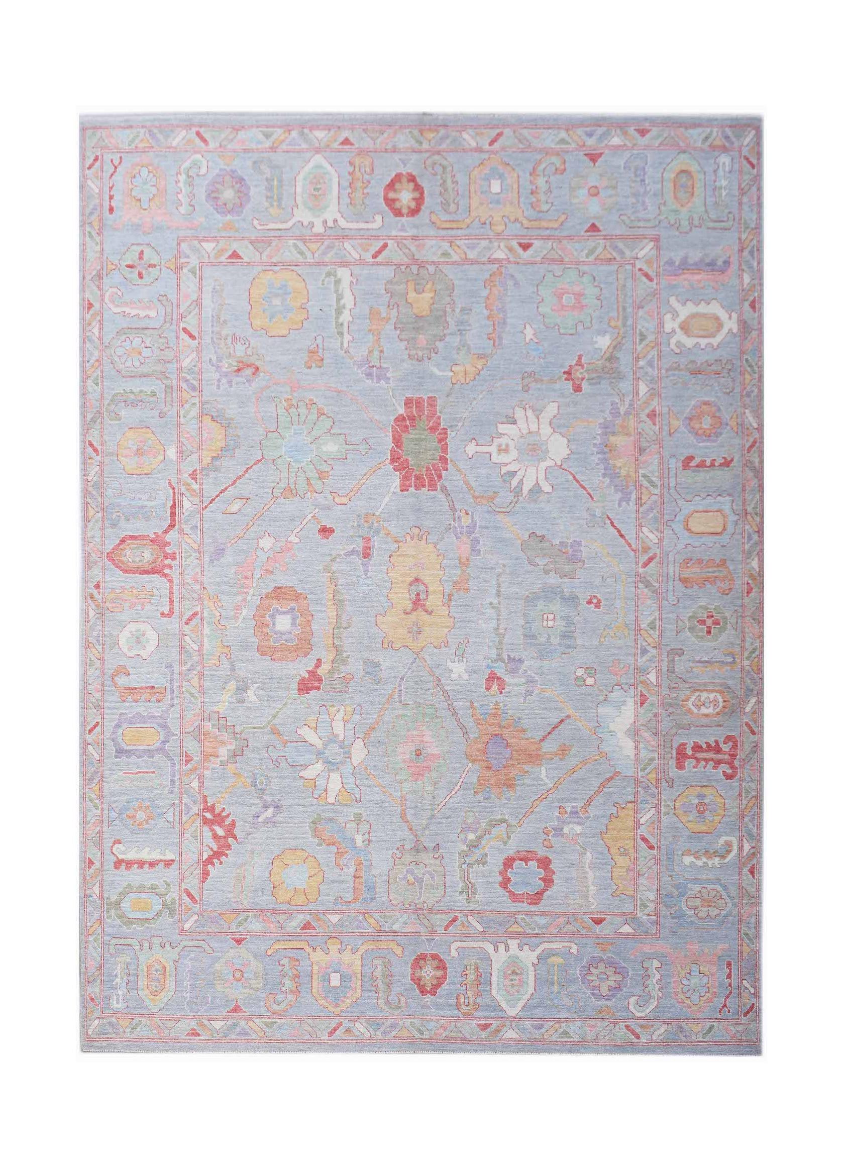 A handwoven transitional Oushak rug featuring a floral pattern in soft pastel tones on a blue field.