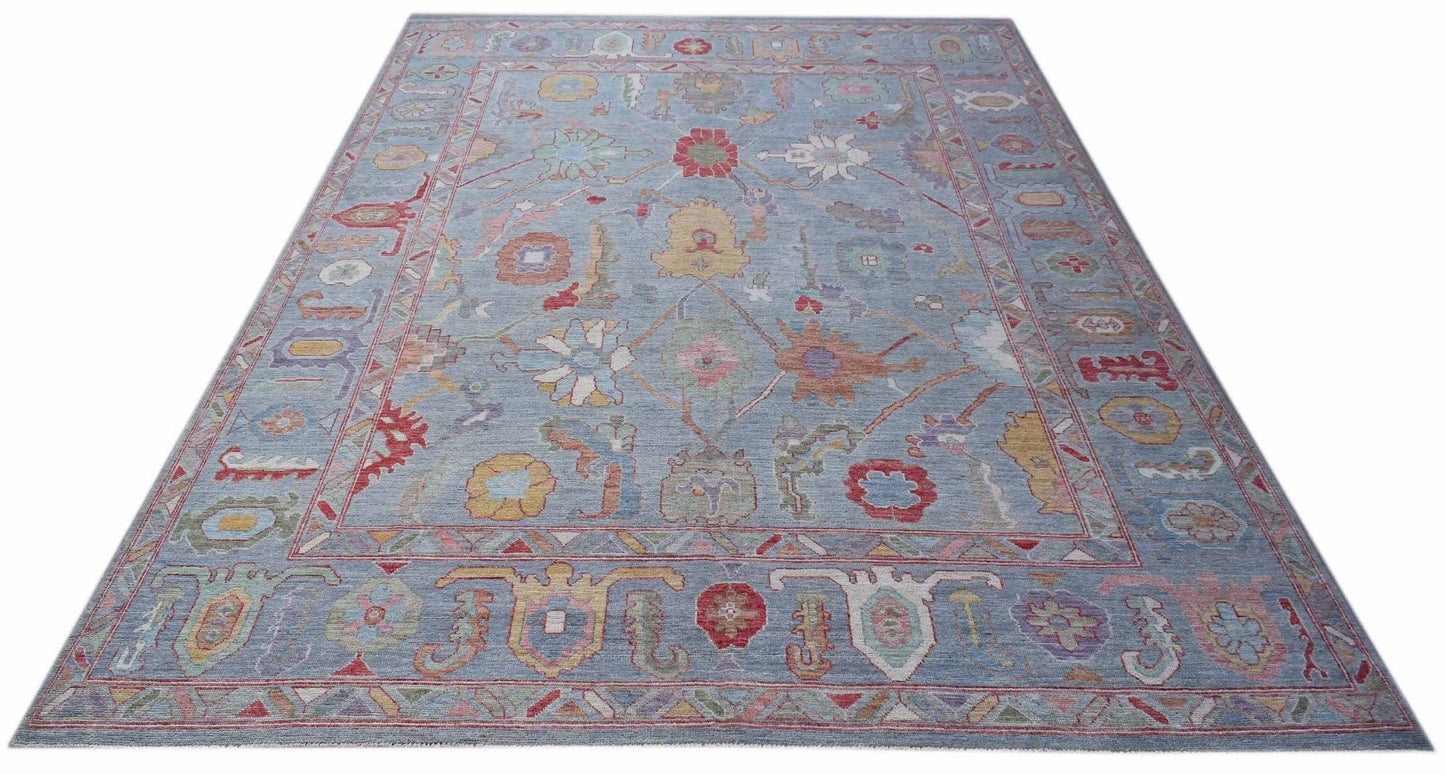A handwoven transitional Oushak rug featuring a floral pattern in soft colors on a blue background.