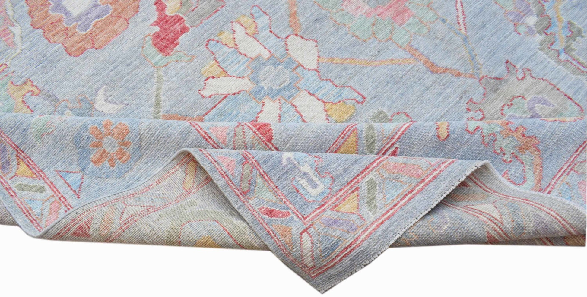 A handwoven transitional Oushak rug featuring a floral pattern in soft pastel colors on blue.