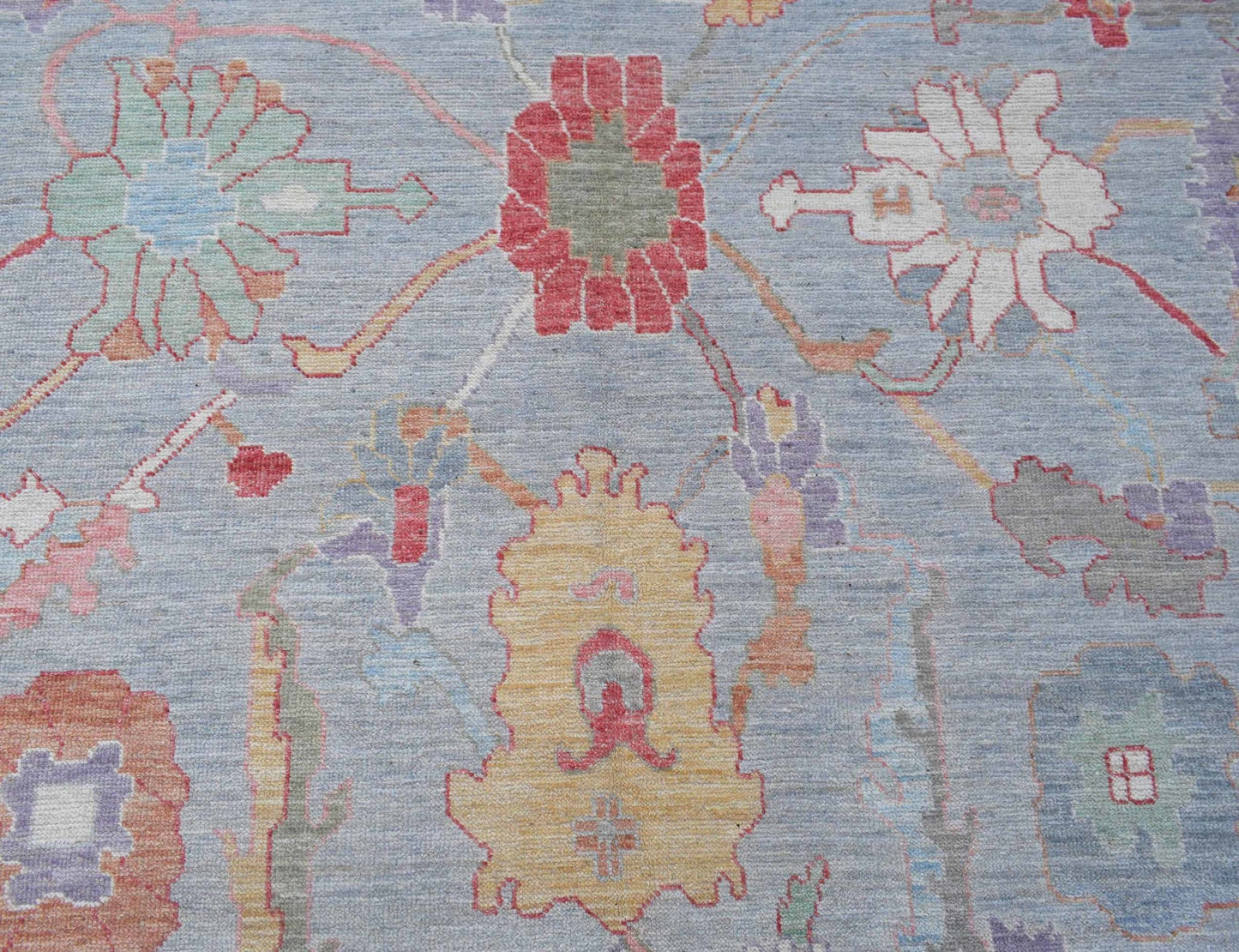 A handwoven transitional Oushak rug featuring a floral pattern in soft, contemporary colors.