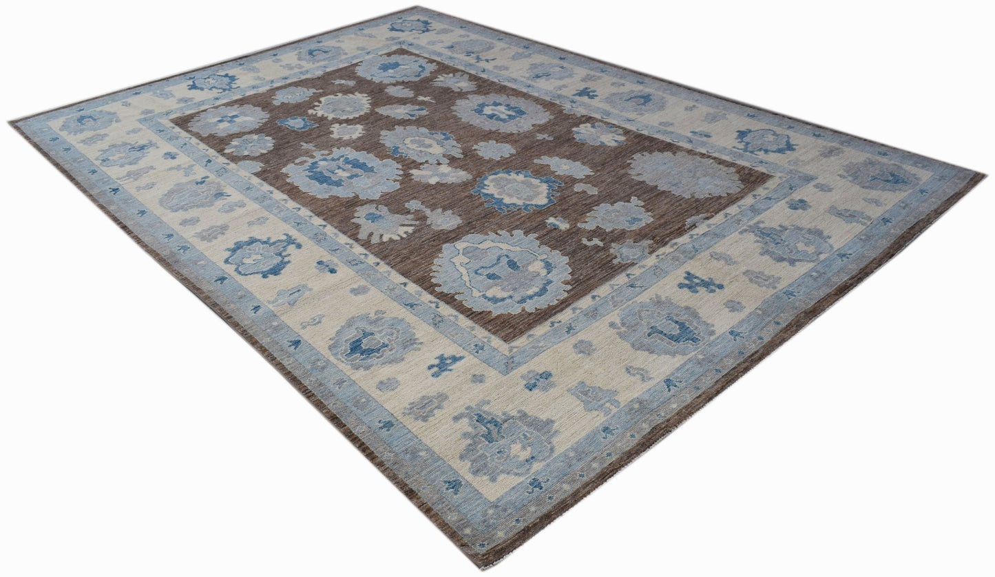 A handwoven transitional Oushak rug featuring a brown field with blue and cream floral patterns.