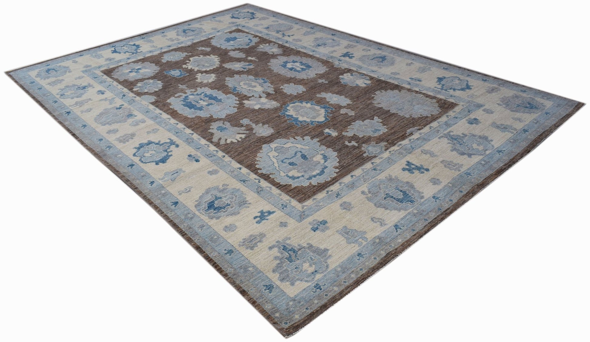 A handwoven transitional Oushak rug featuring a brown field with blue and cream floral patterns.