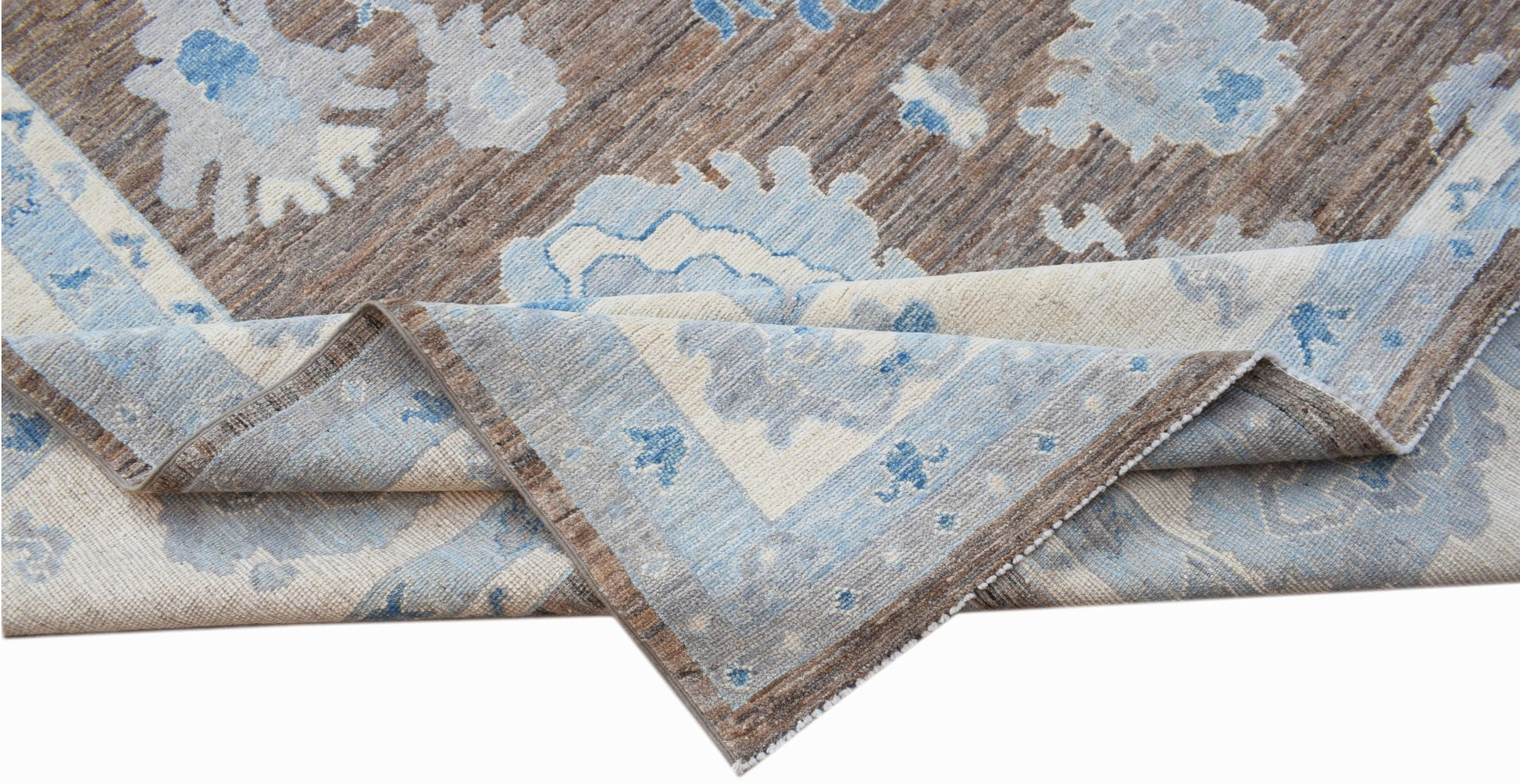 A handwoven transitional Oushak rug featuring a floral pattern in shades of blue and brown.