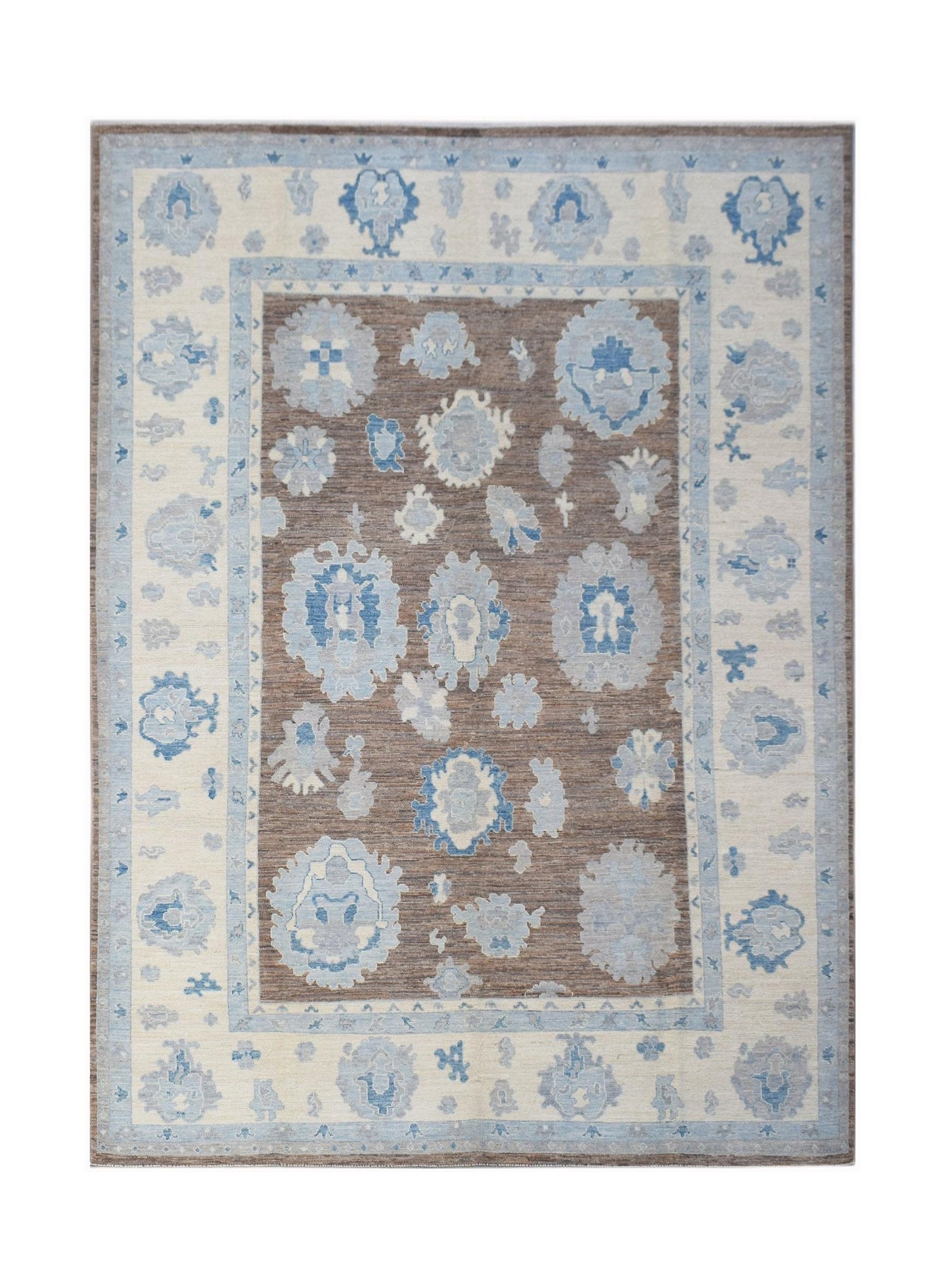 A handwoven transitional Oushak rug featuring blue floral motifs on a brown field and cream border.