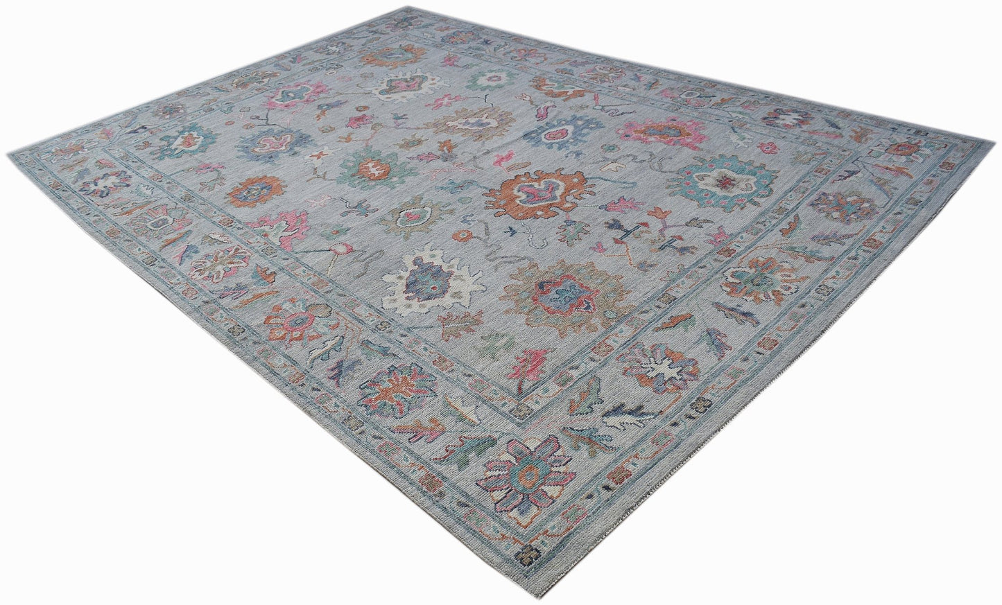 A handwoven transitional Oushak rug featuring a floral pattern in soft, multi-colored tones.