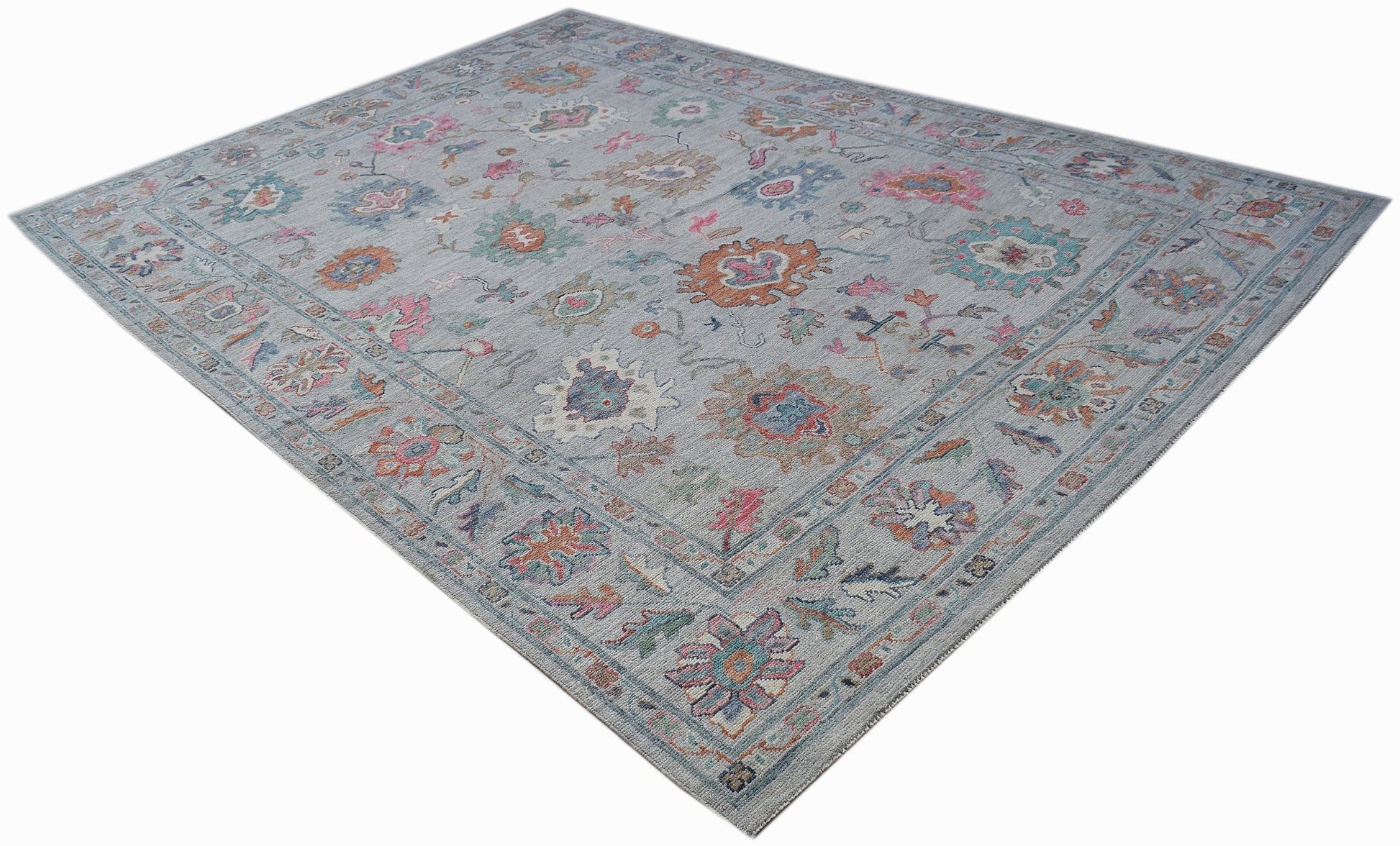 A handwoven transitional Oushak rug featuring a floral pattern in soft, multi-colored tones.