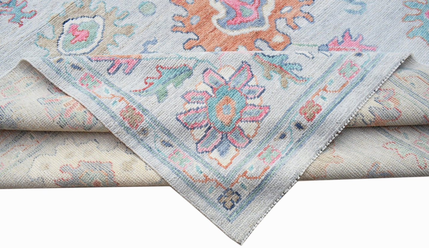 A handwoven transitional Oushak rug featuring a floral pattern in soft pastel tones.