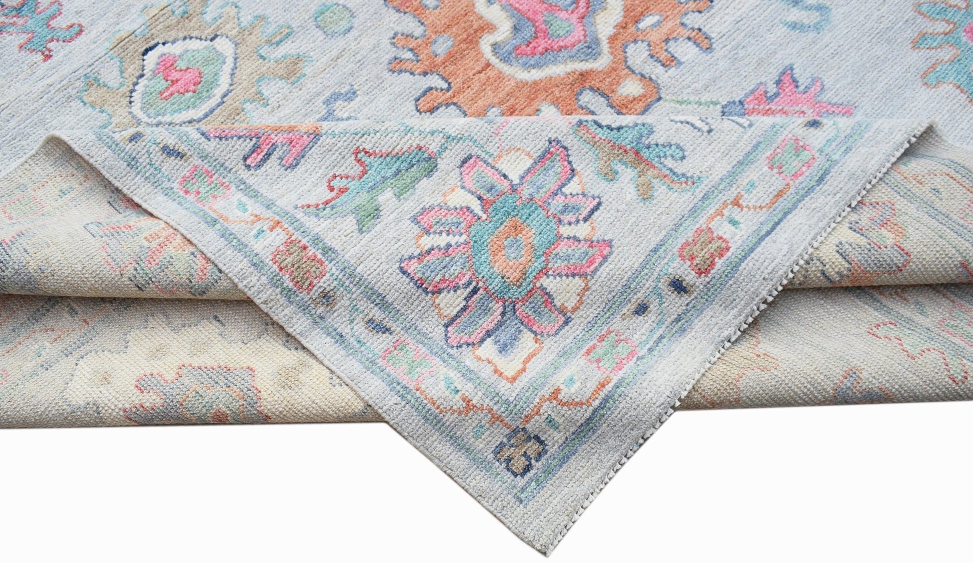 A handwoven transitional Oushak rug featuring a floral pattern in soft pastel tones.