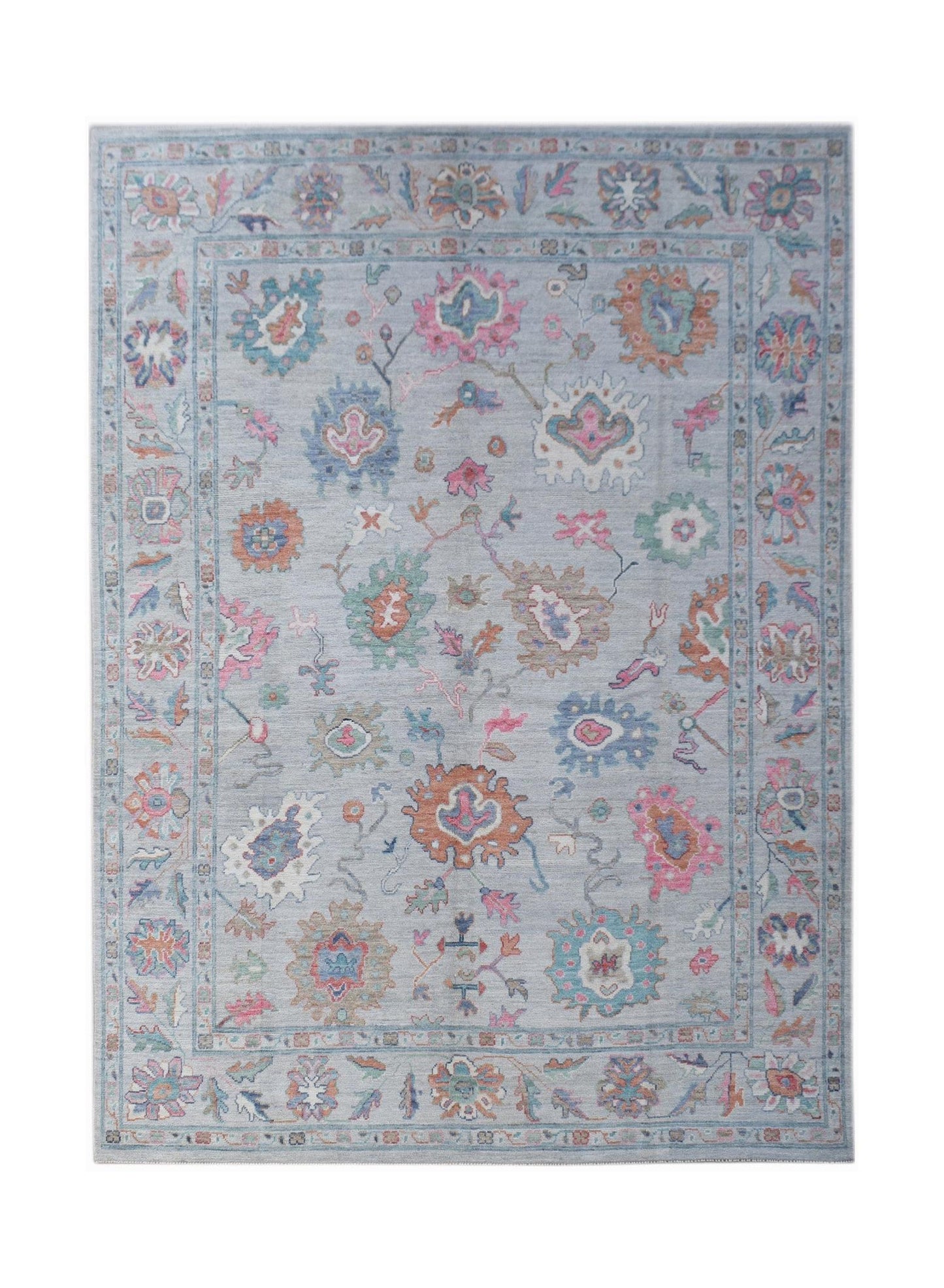 A handwoven transitional Oushak rug featuring a floral pattern in soft colors on a light blue base.