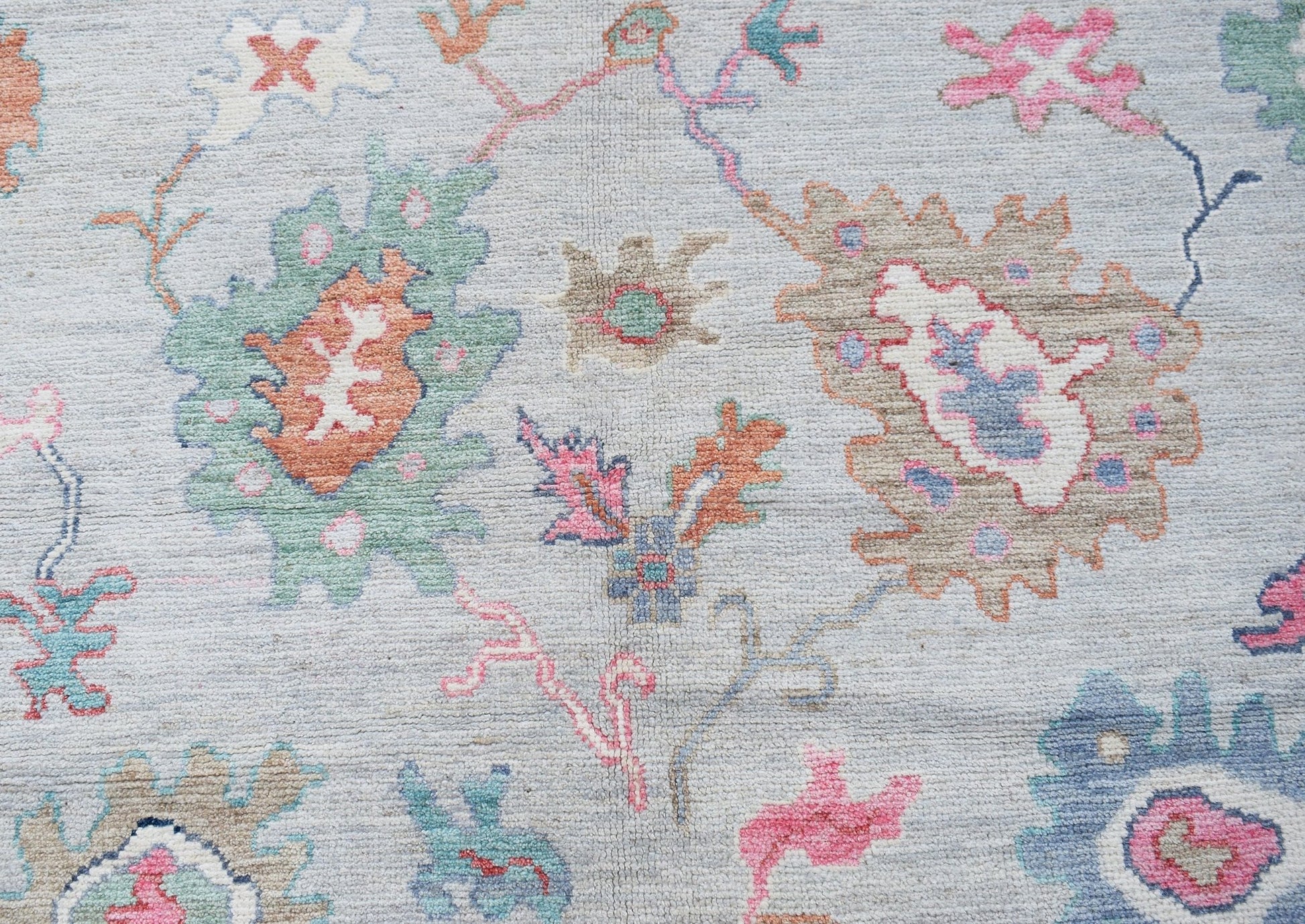 A transitional Oushak rug featuring a light blue background with colorful floral patterns.
