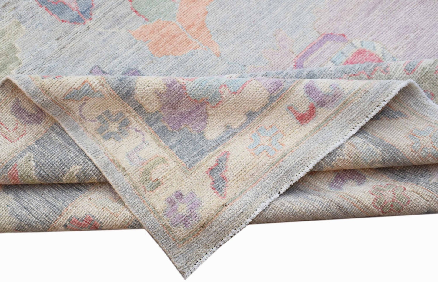 A handwoven transitional Oushak rug featuring a floral pattern in soft pastel tones.