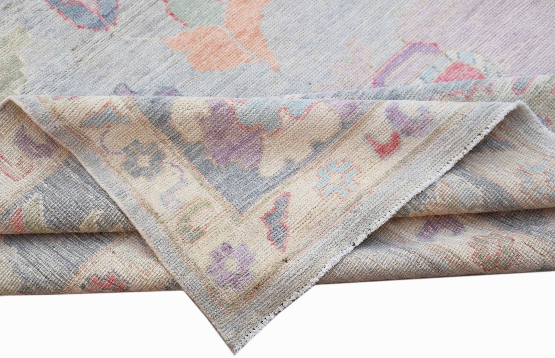 A handwoven transitional Oushak rug featuring a floral pattern in soft pastel tones.