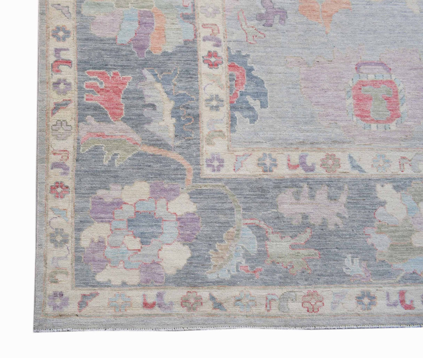 A handwoven transitional Oushak rug featuring a floral pattern in soft blue and pastel tones.