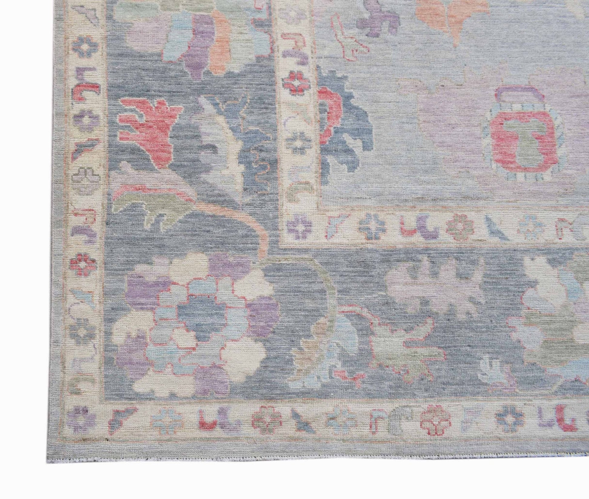 A handwoven transitional Oushak rug featuring a floral pattern in soft blue and pastel tones.