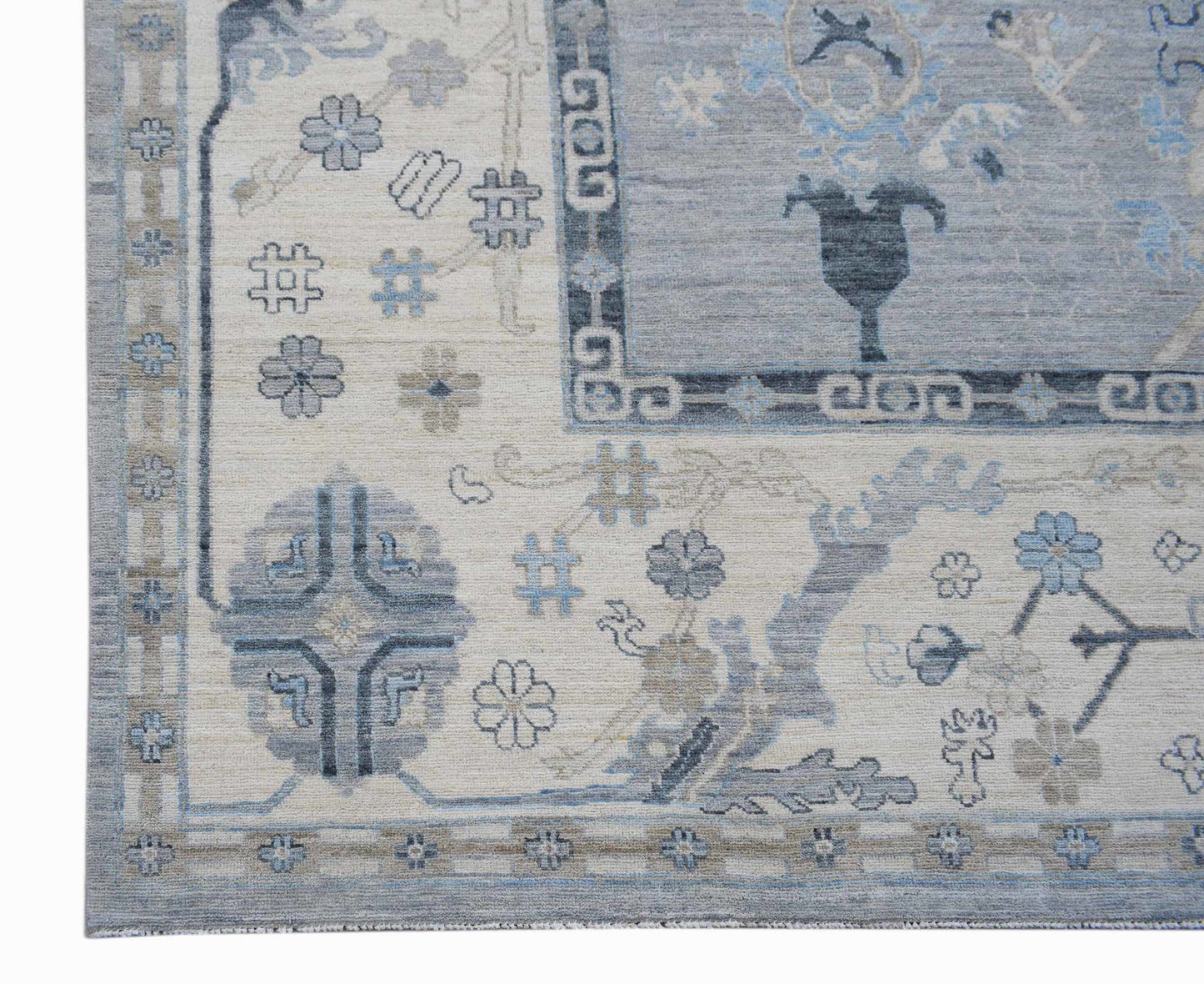 A handwoven transitional Oushak rug featuring a floral pattern in shades of blue and cream.