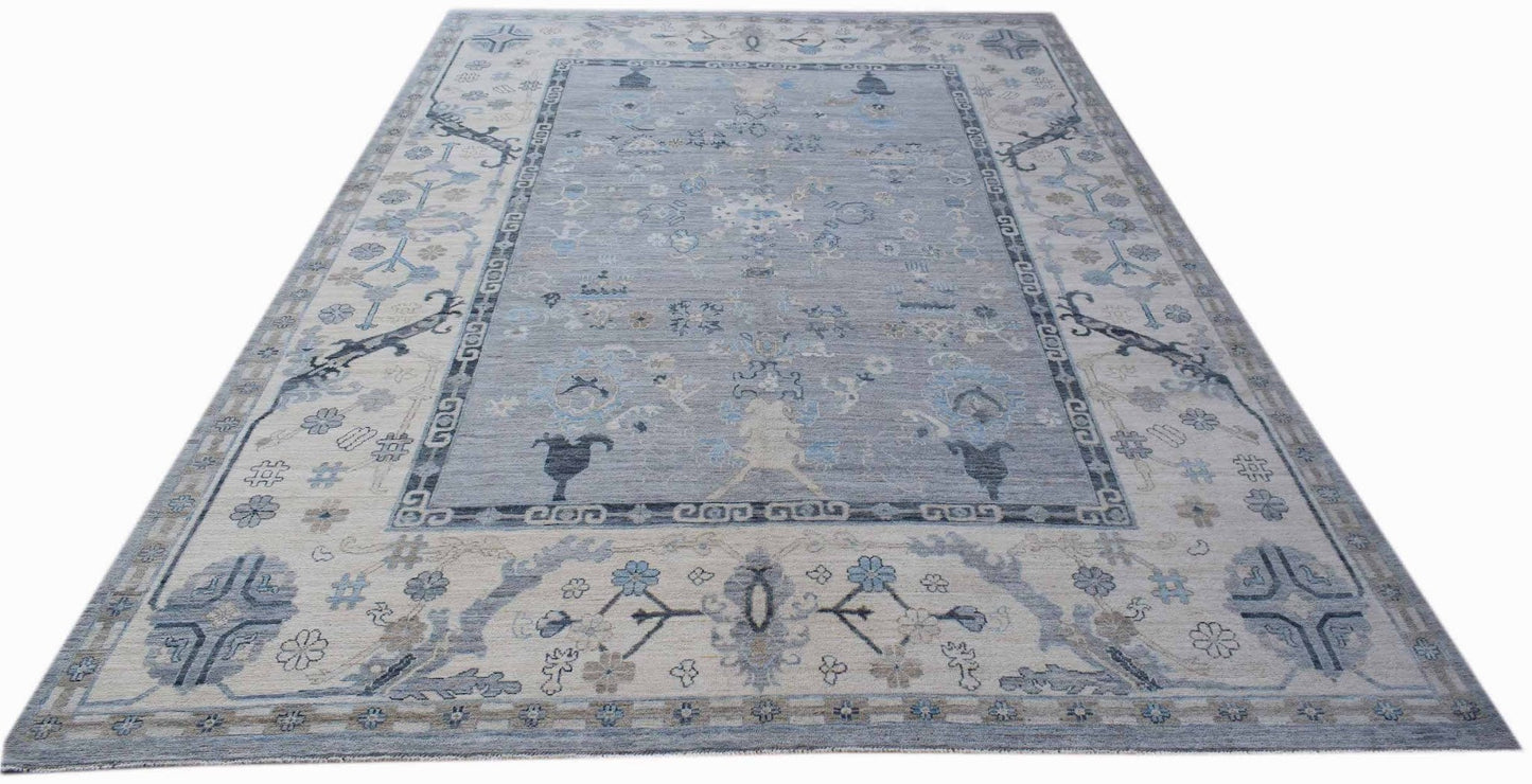 A handwoven transitional Oushak rug featuring a floral pattern in shades of blue and cream.