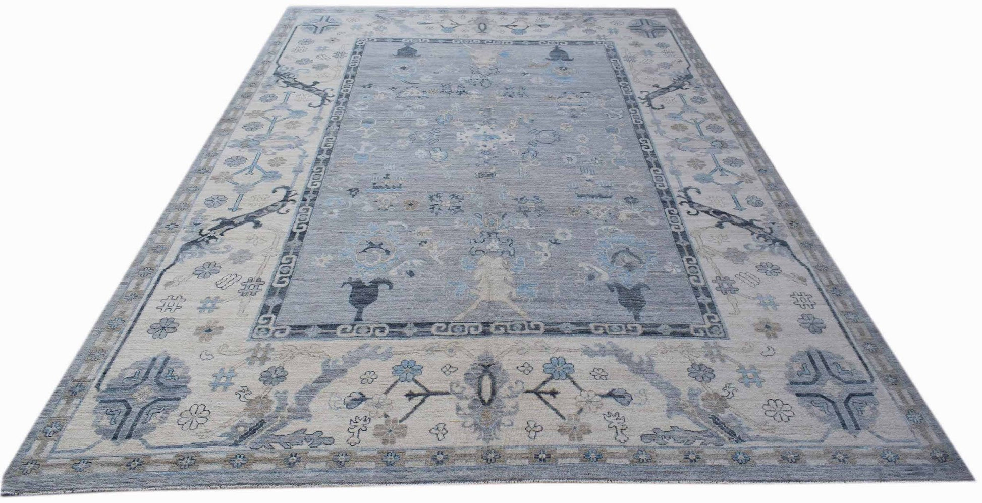 A handwoven transitional Oushak rug featuring a floral pattern in shades of blue and cream.