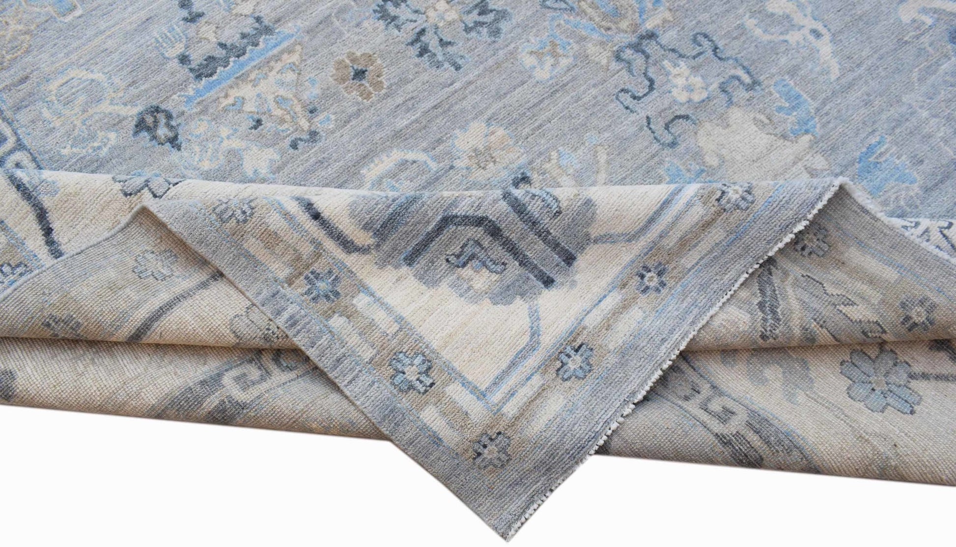 A handwoven transitional Oushak rug featuring a floral pattern in shades of blue and beige.