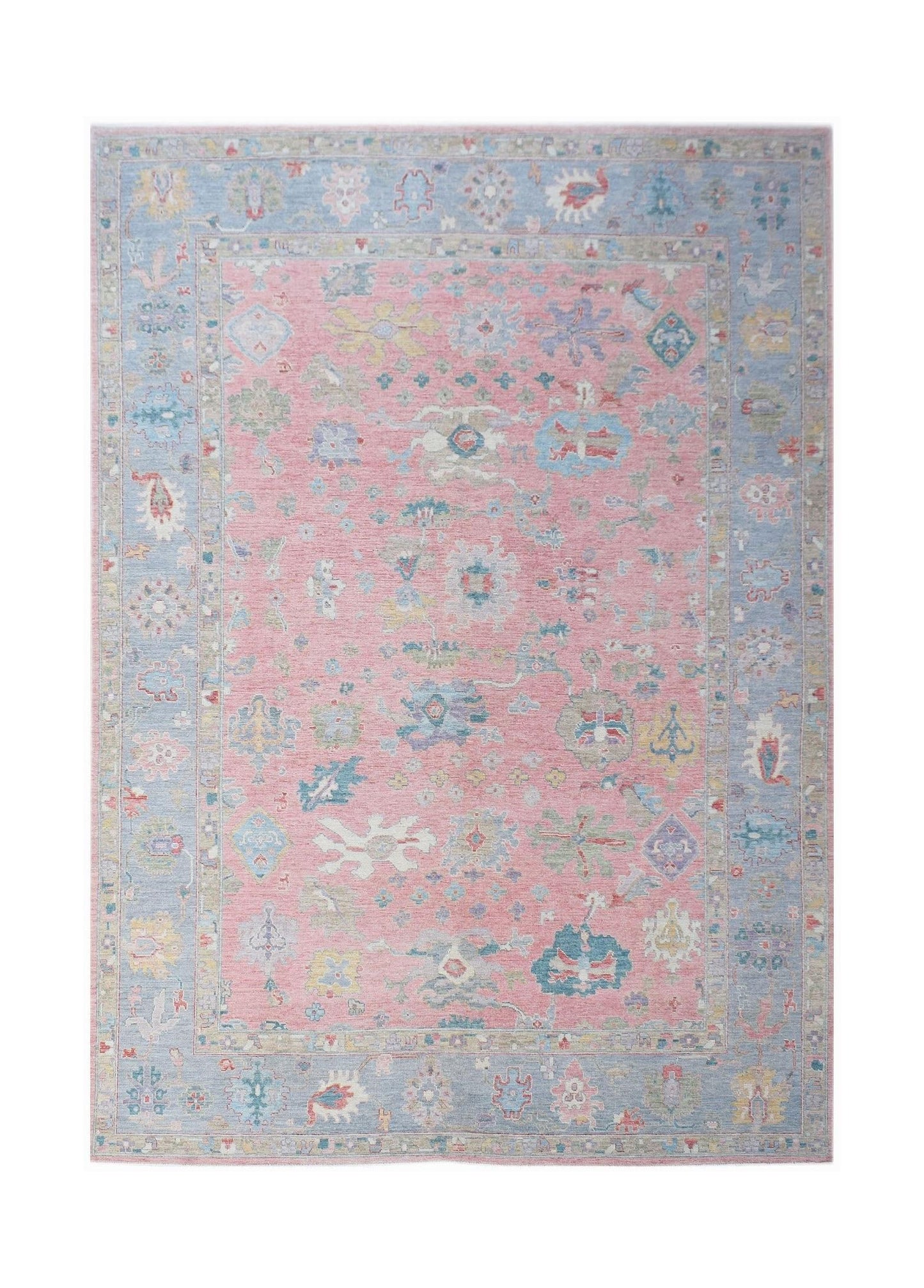 A handwoven transitional Oushak rug featuring a floral pattern in pink and blue tones.
