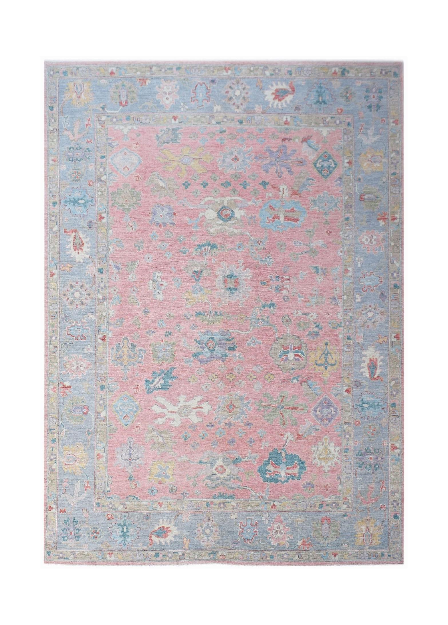 A handwoven transitional Oushak rug featuring a floral pattern in pink and blue tones.