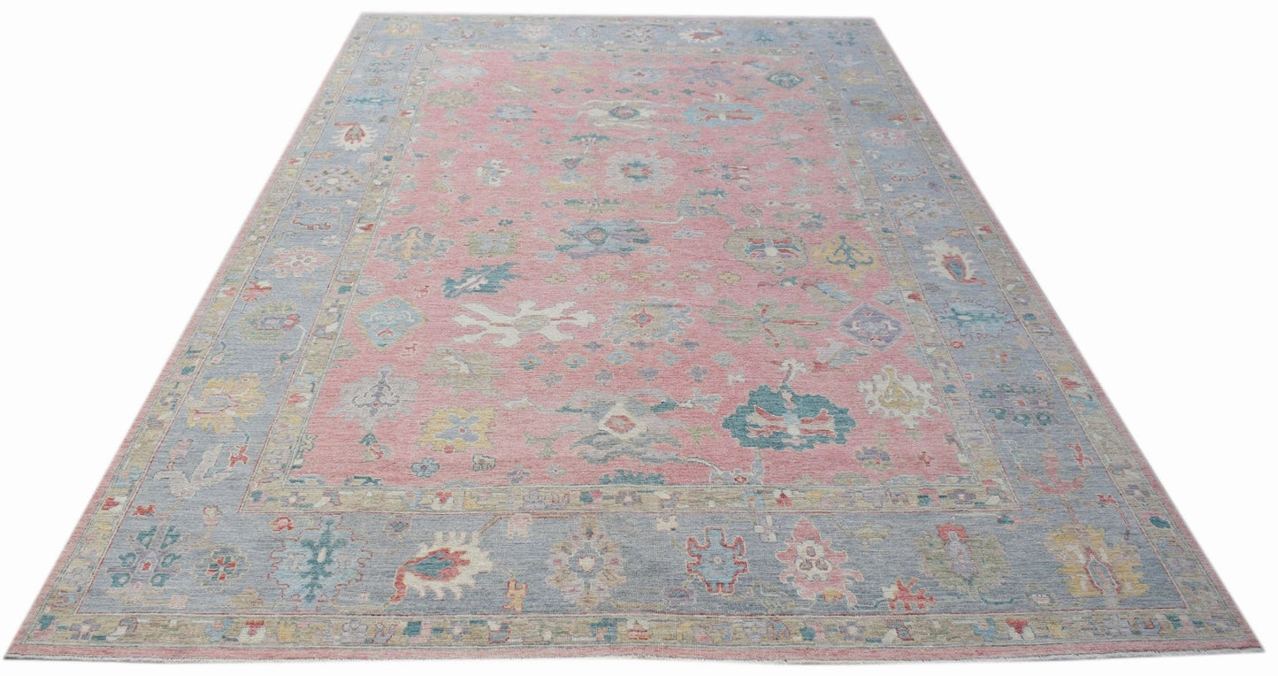A handwoven transitional Oushak rug featuring a floral pattern in pink and blue tones.