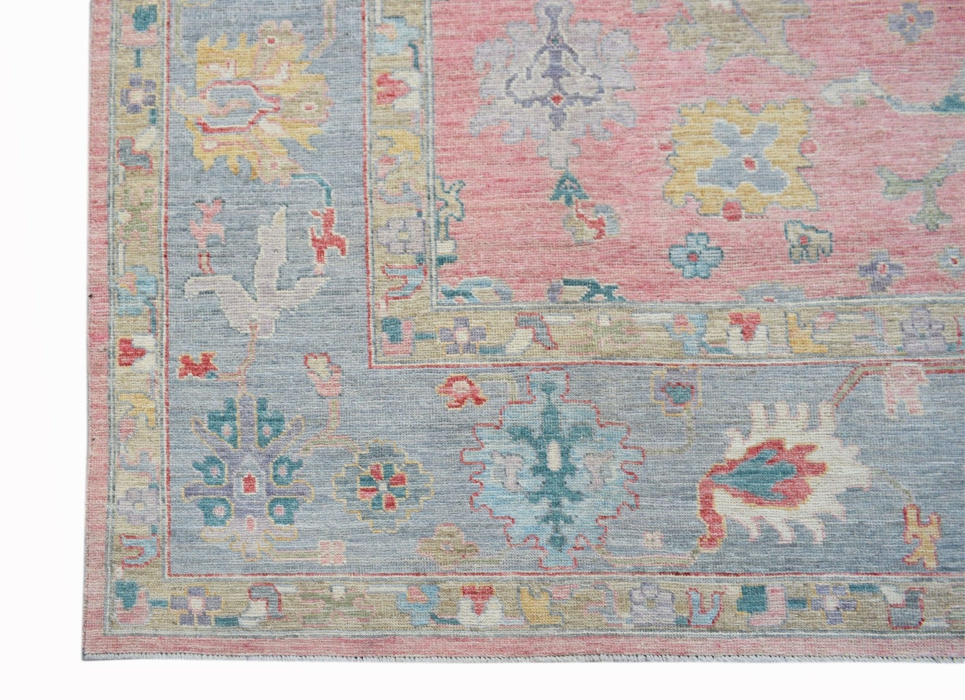 A handwoven Oushak rug featuring a floral pattern in soft pink, blue, and yellow tones.
