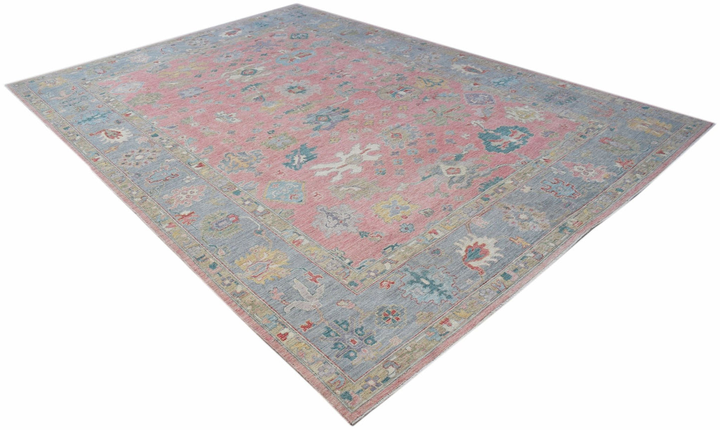 A transitional Oushak rug featuring a floral pattern in pink, blue, and neutral tones.