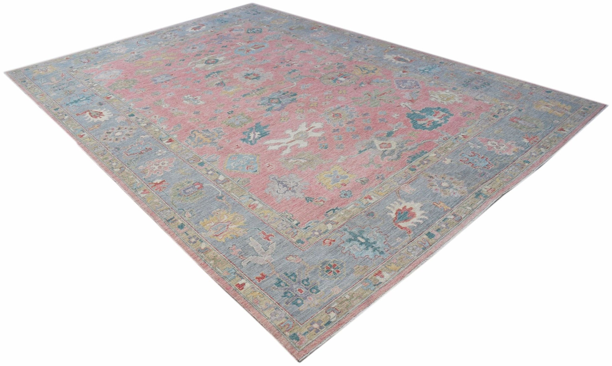 A transitional Oushak rug featuring a floral pattern in pink, blue, and neutral tones.