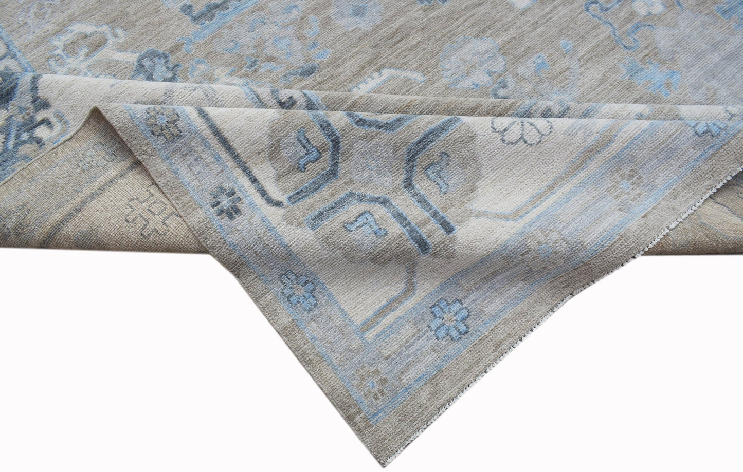 A handwoven transitional Oushak rug featuring a light beige and blue floral pattern.