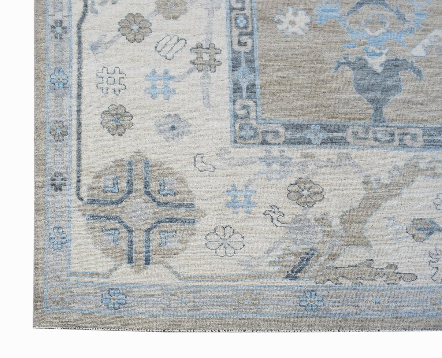 A handwoven transitional Oushak rug featuring a floral pattern in blue, beige, and grey tones.