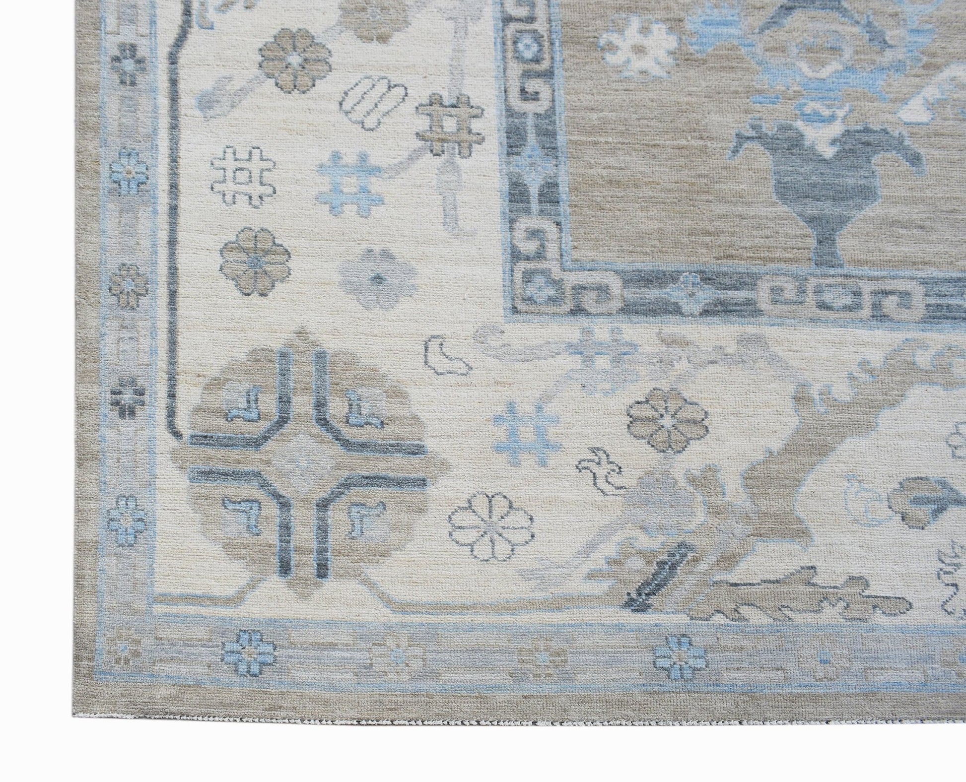A handwoven transitional Oushak rug featuring a floral pattern in blue, beige, and grey tones.