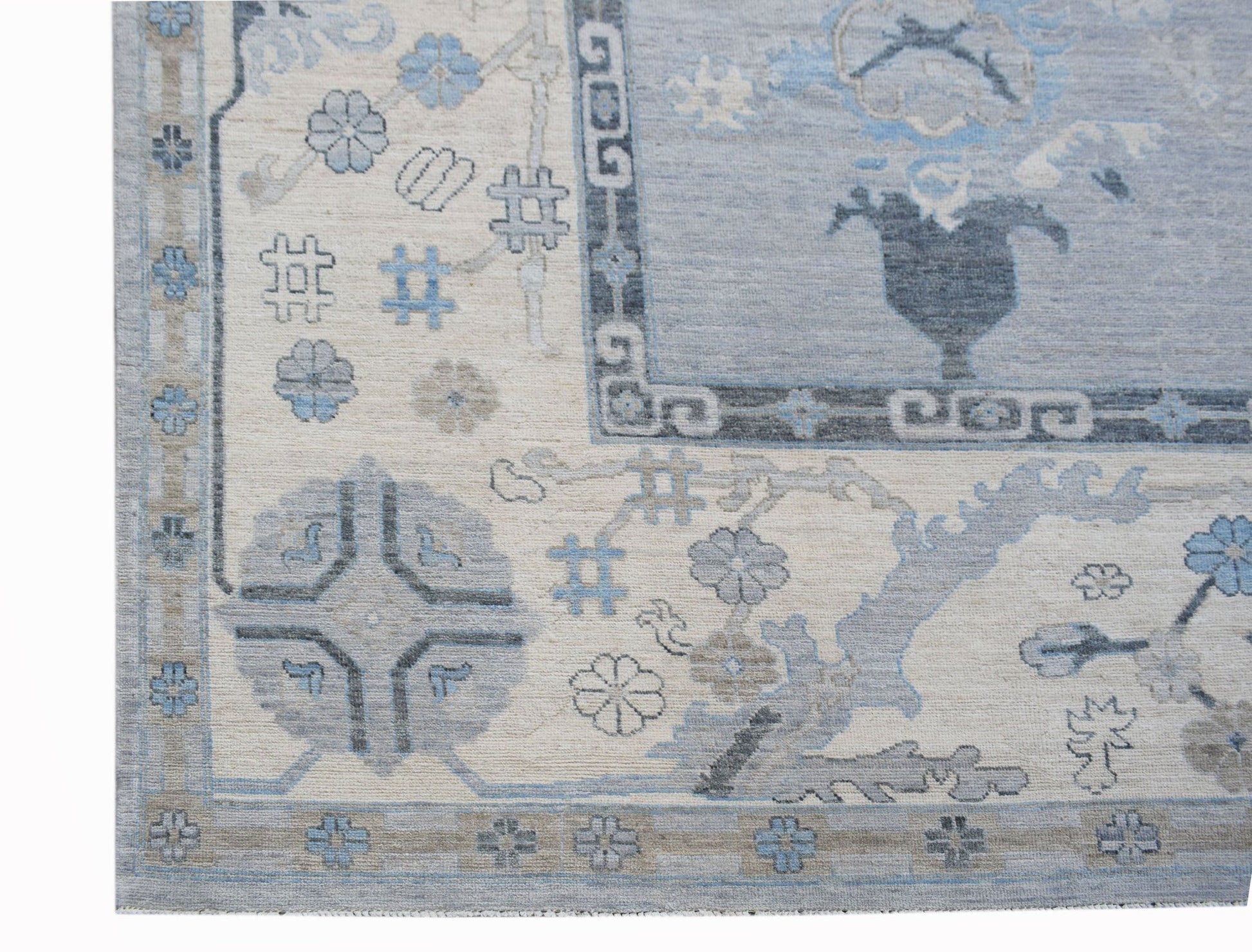 A transitional Oushak rug featuring a blue and cream floral pattern with a geometric border.