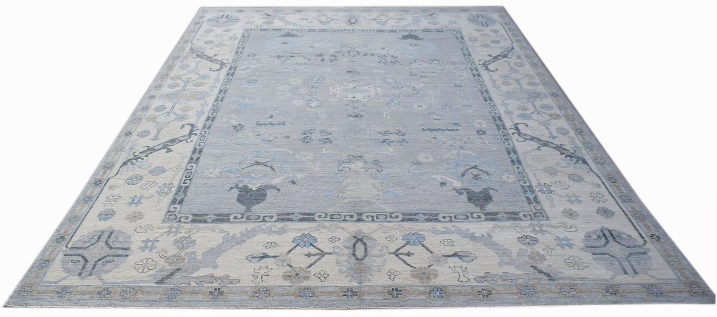 A transitional Oushak rug featuring a light blue floral pattern on a soft grey background.