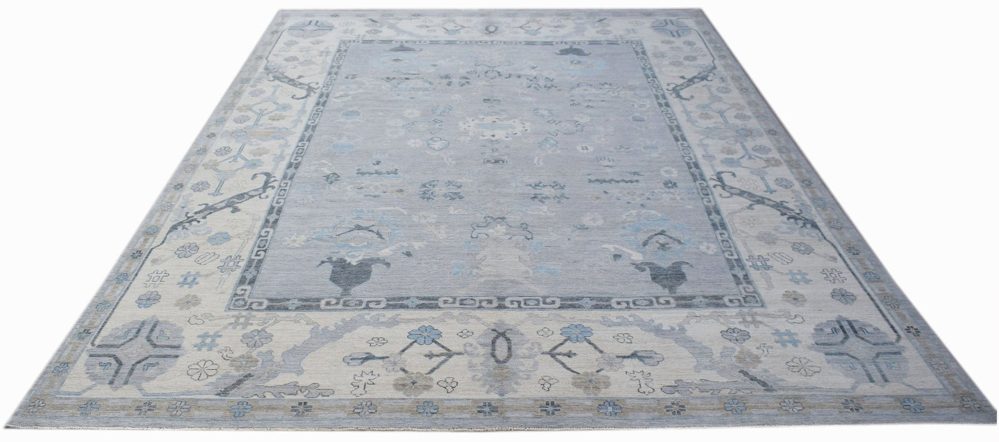 A transitional Oushak rug featuring a light blue floral pattern on a soft grey background.