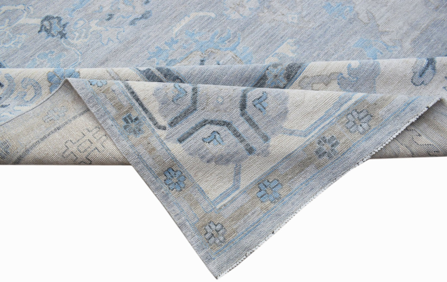 A handwoven transitional Oushak rug featuring a light blue and grey floral pattern.