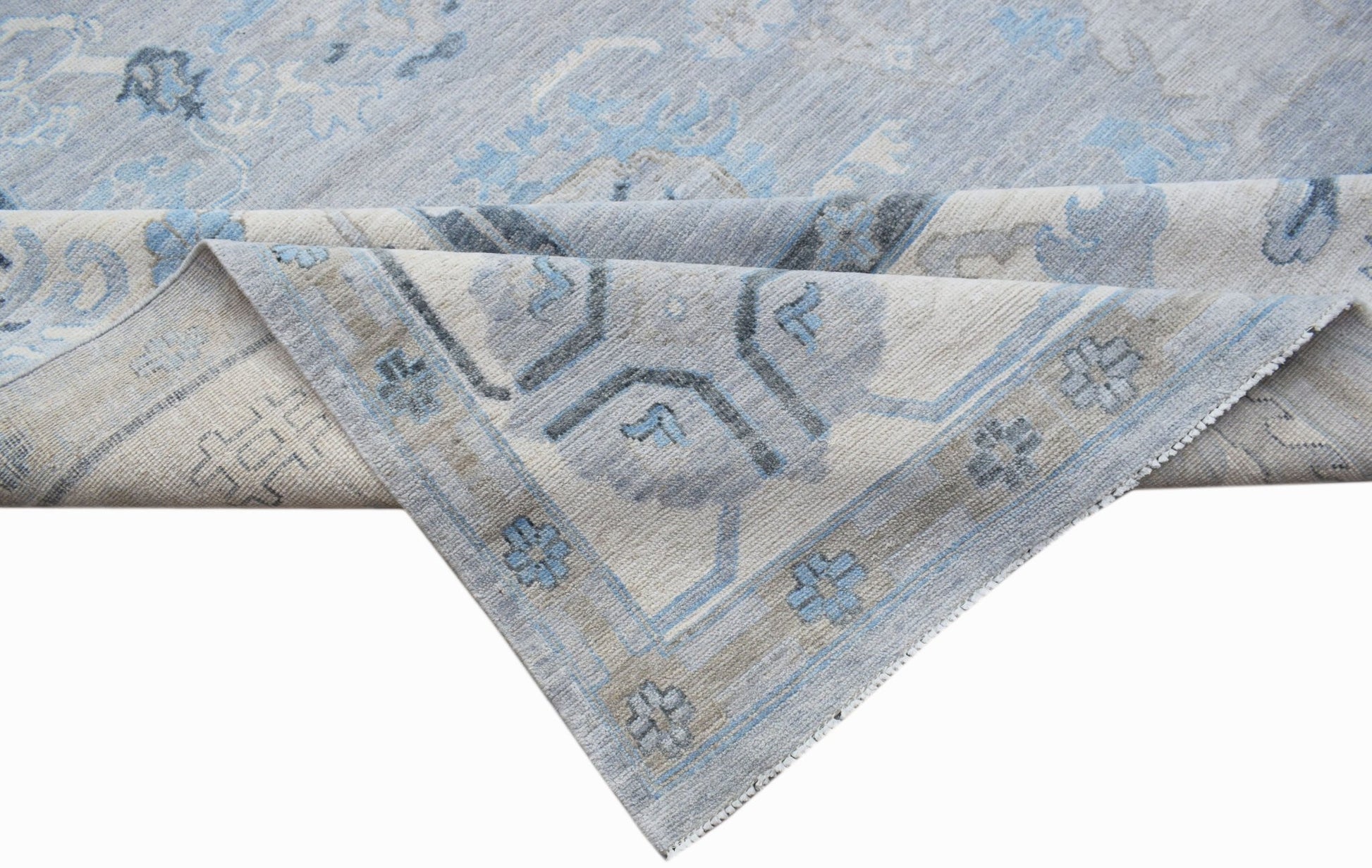 A handwoven transitional Oushak rug featuring a light blue and grey floral pattern.