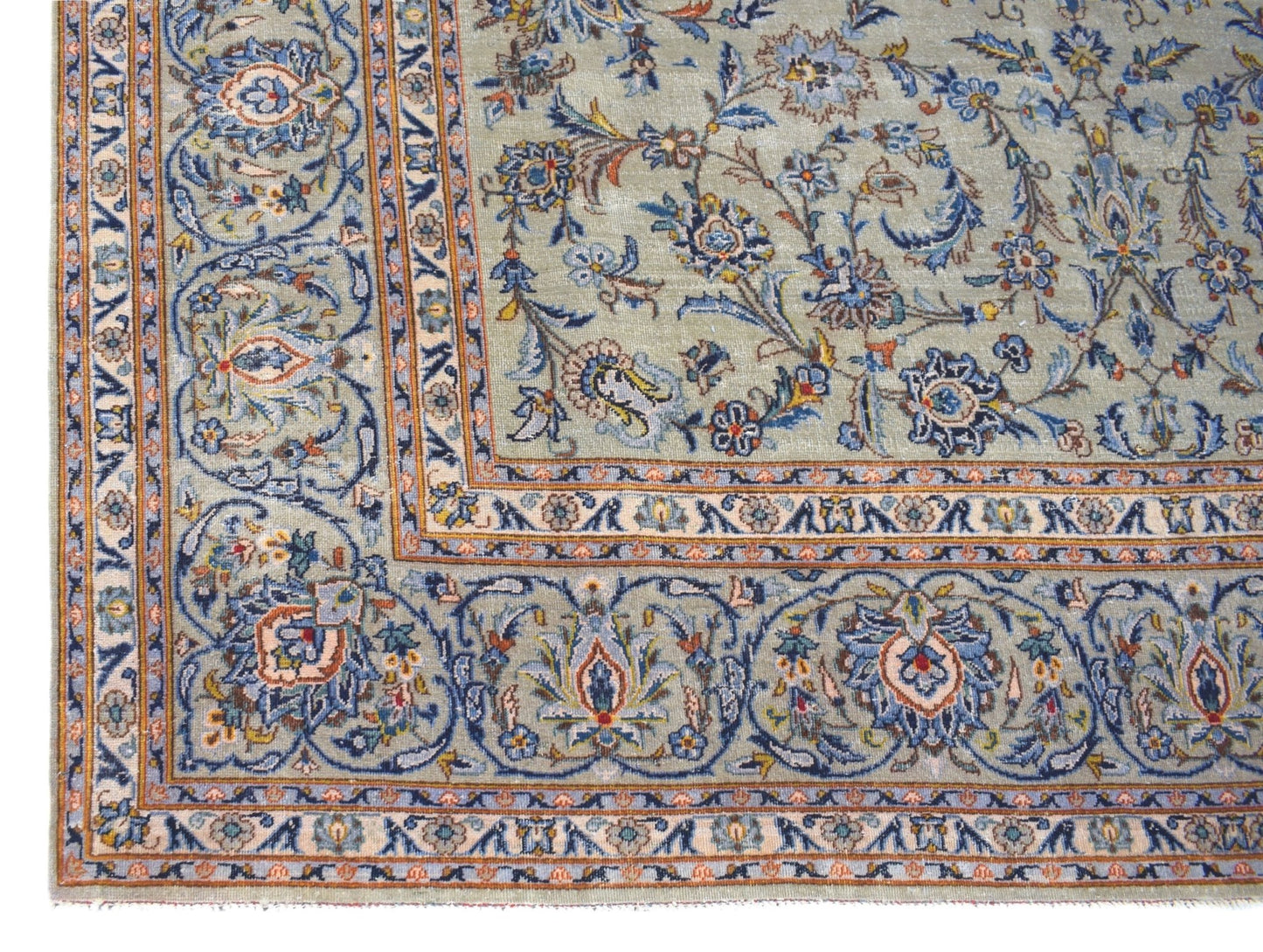 A vintage Persian Kashan rug featuring intricate floral patterns in blue and sage green tones.