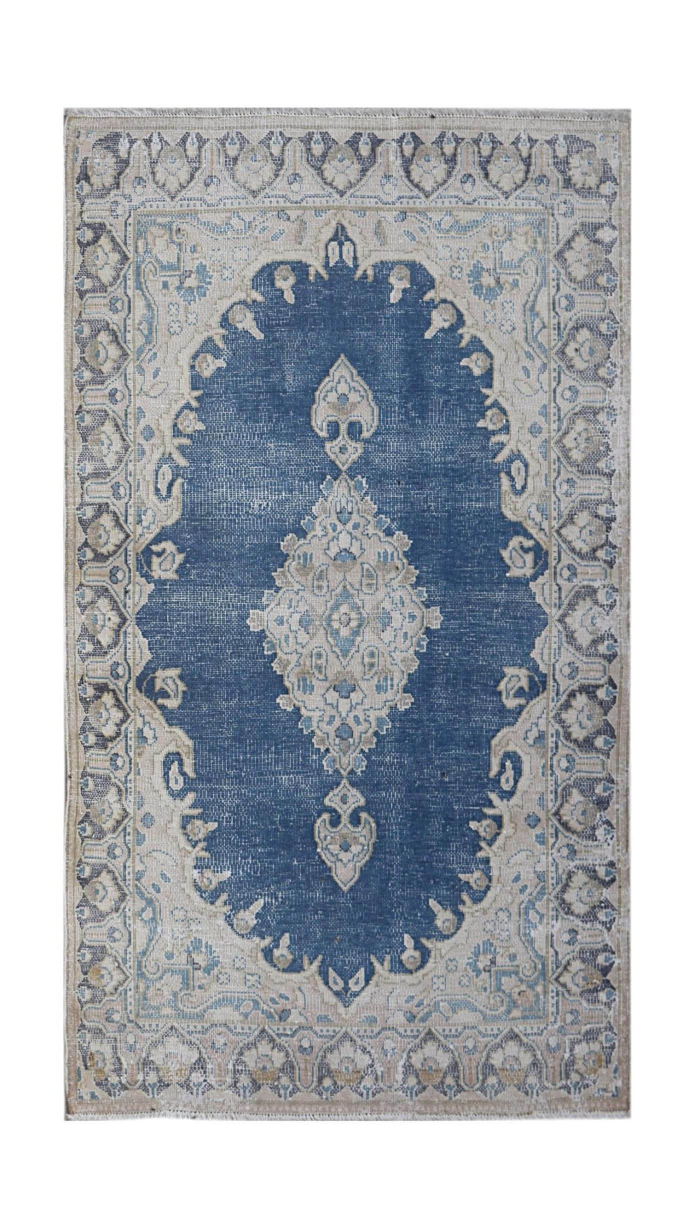 A vintage Persian Kerman rug featuring a central medallion on a blue field with floral borders.